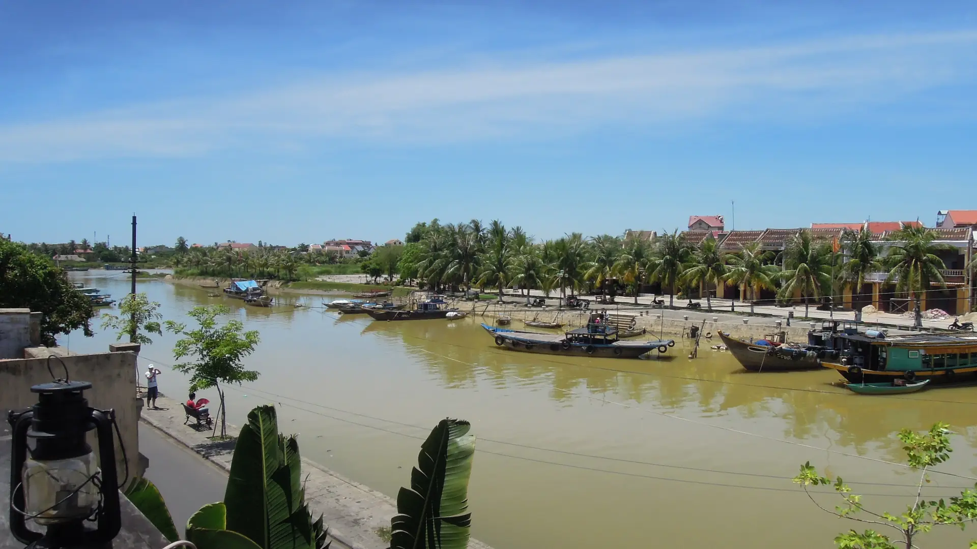 Boats, palms and waterside houses along a river in wider Hoi An