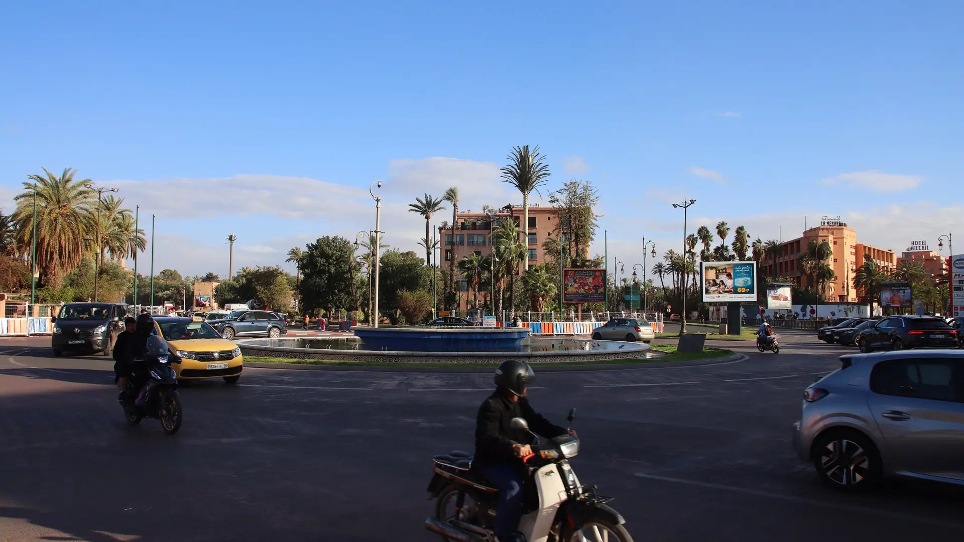 Palm-lined Guéliz roundabout and modern Marrakech buildings under clear sky