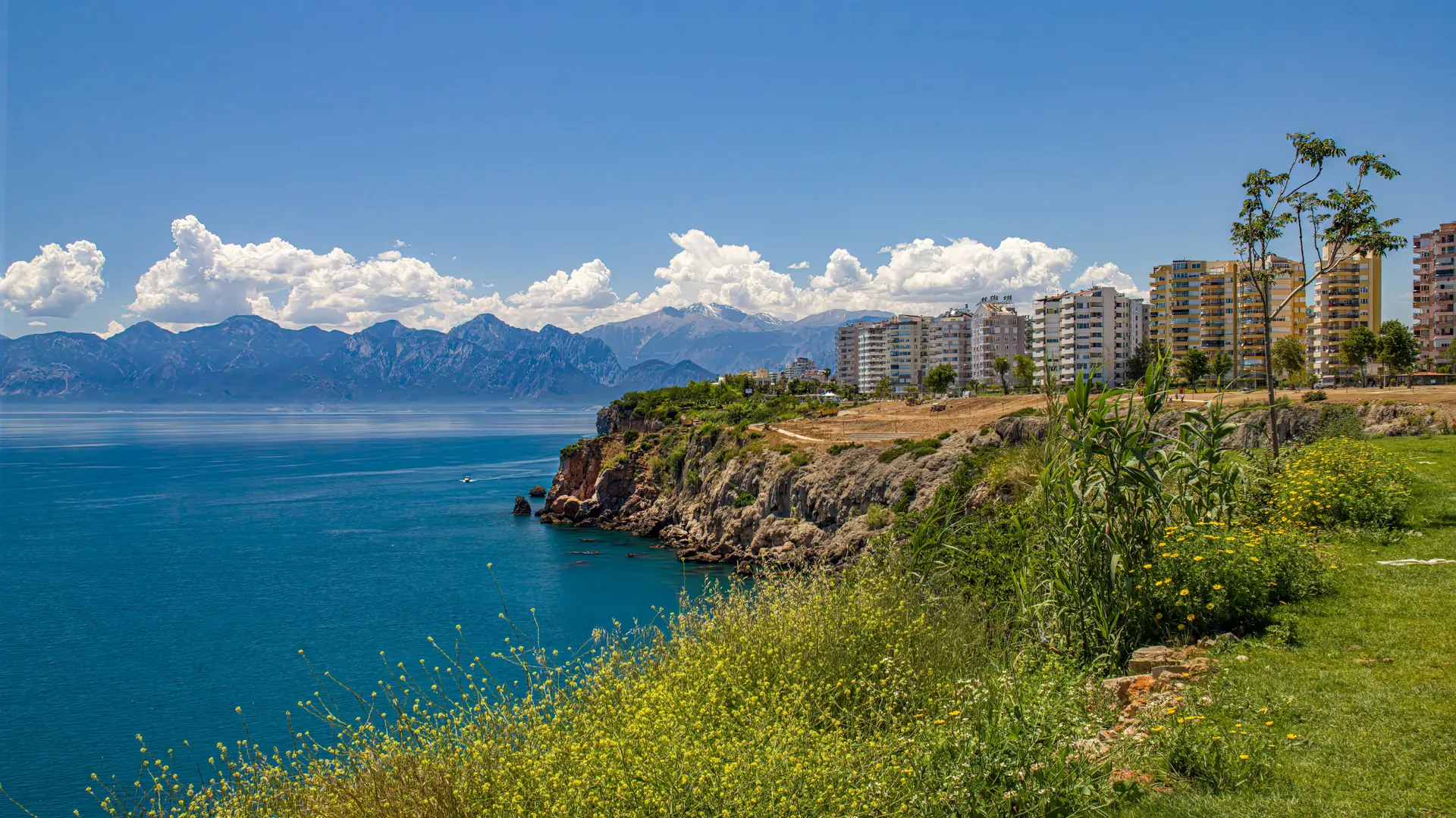 Antalya city sea cliffs and the western bay, with mountains beyond the water in sunshine