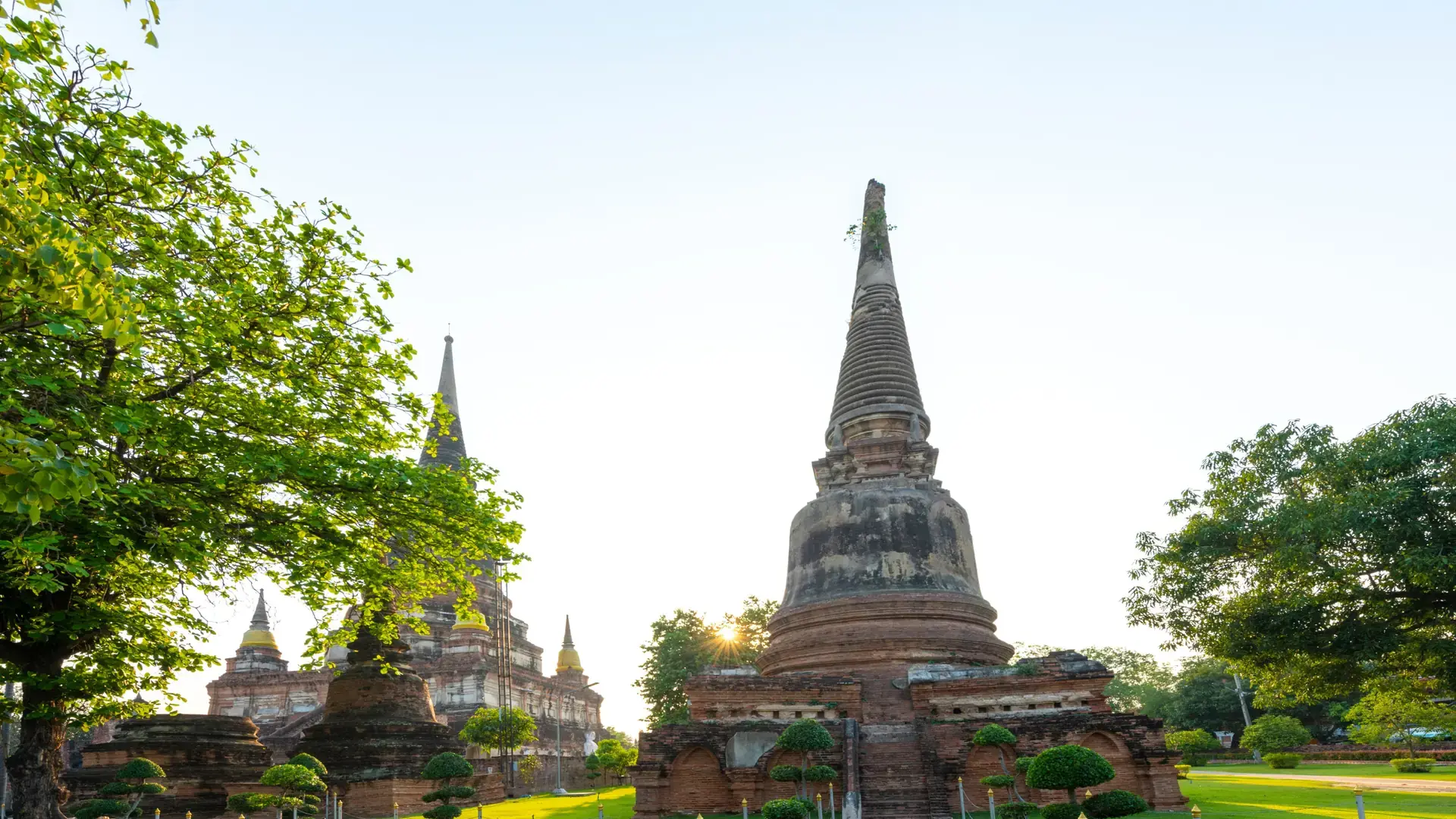 Historic brick stupas and green temple grounds in Ayutthaya, a wider city scene