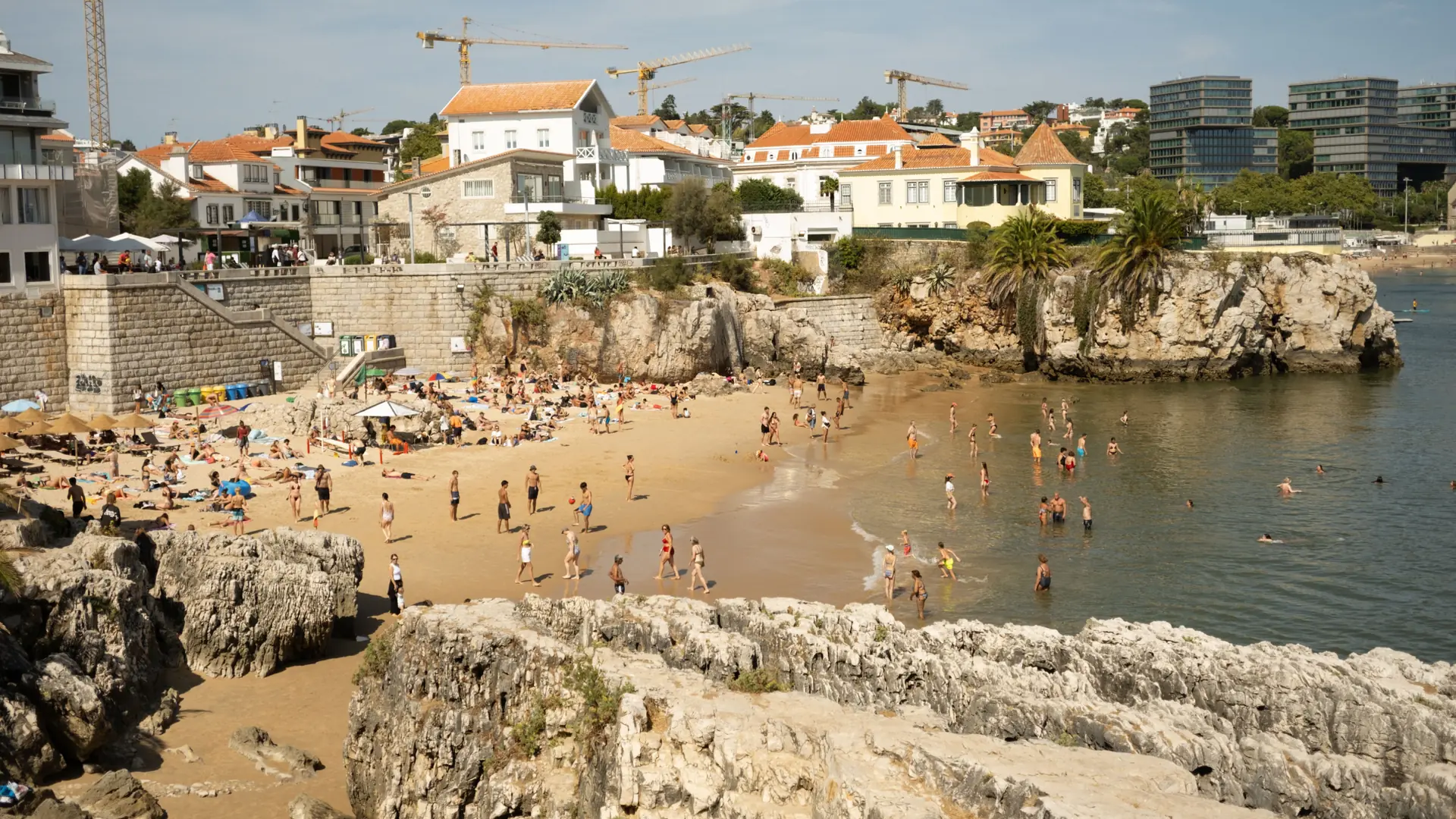 Travellers relaxing on a sheltered sandy beach beside Cascais bay