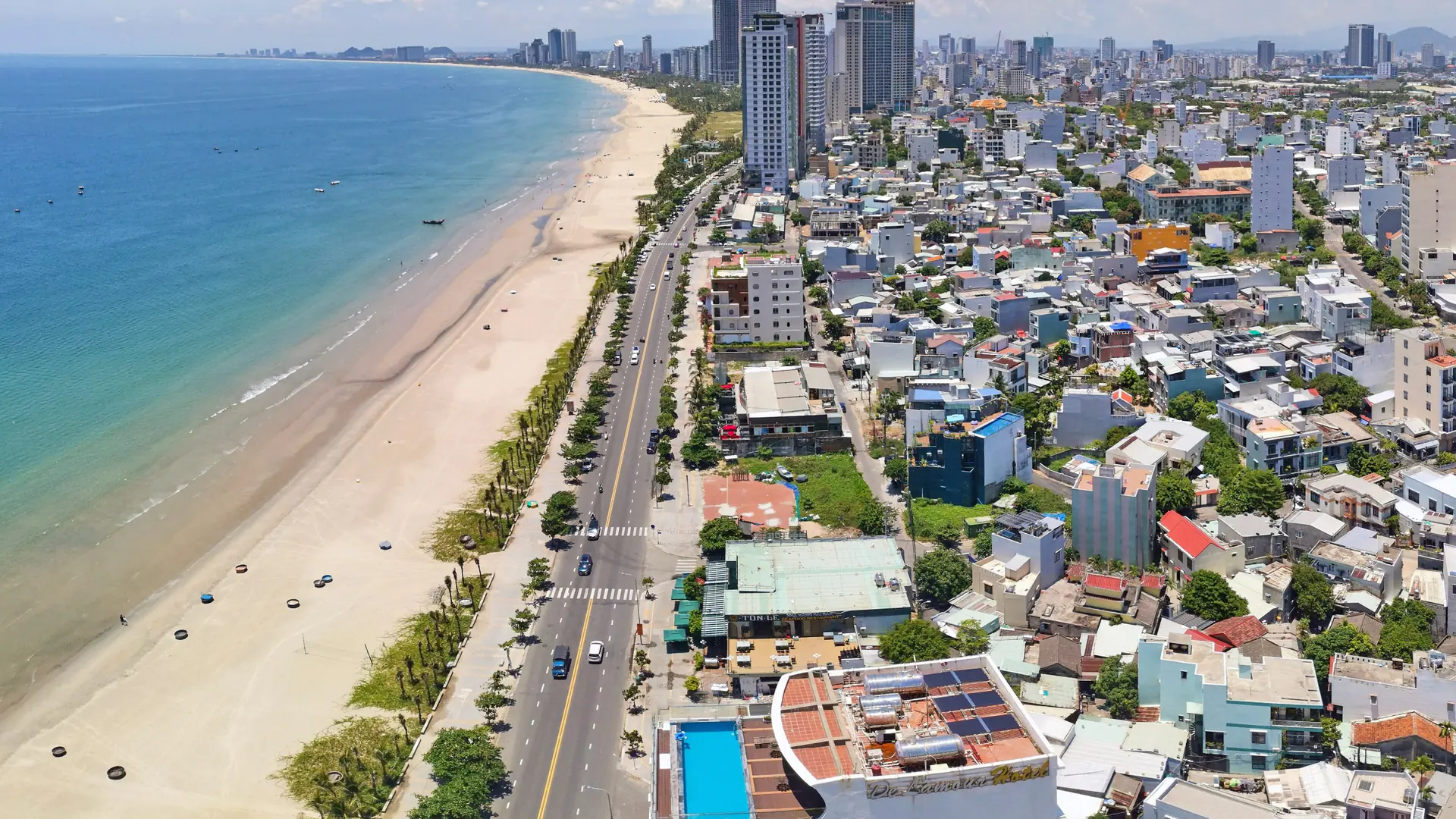 Aerial view along the sunlit Da Nang beachfront toward the city
