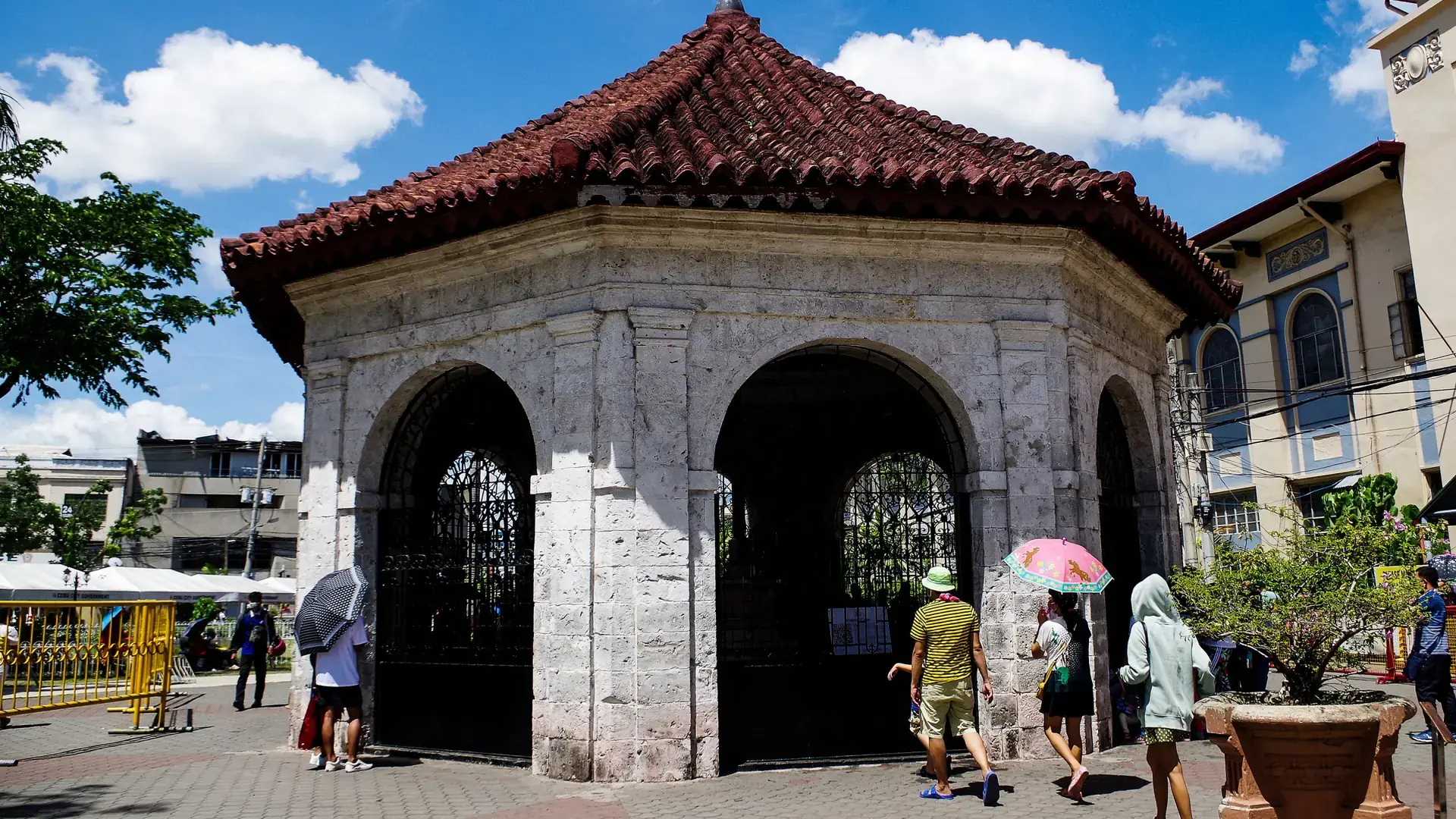 Visitors beside the stone pavilion and red-tiled roof of Magellan’s Cross in Cebu City