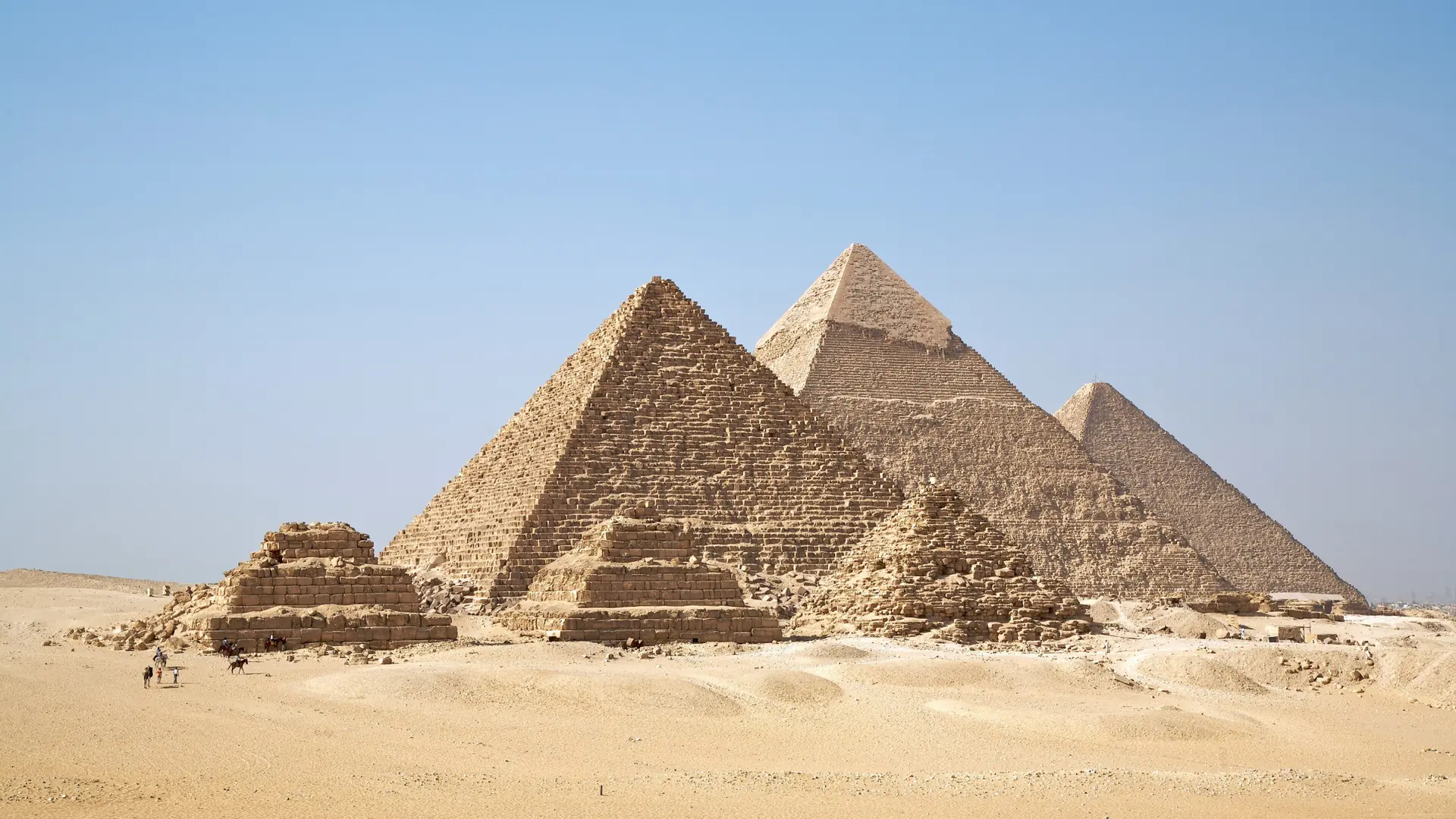 Giza pyramids and smaller queens’ pyramids across the sunlit desert plateau