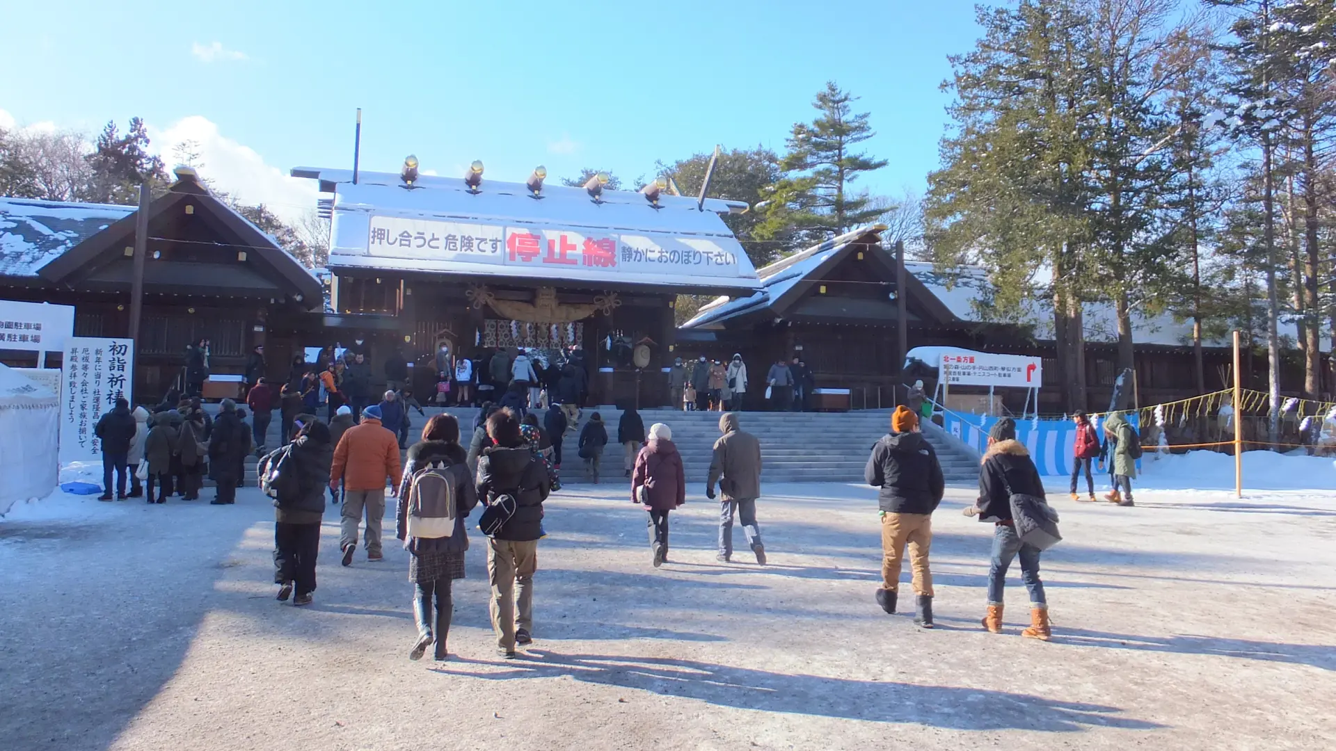Visitors approach Hokkaido Shrine in Sapporo on a sunny winter day, with snow covering the roof and courtyard