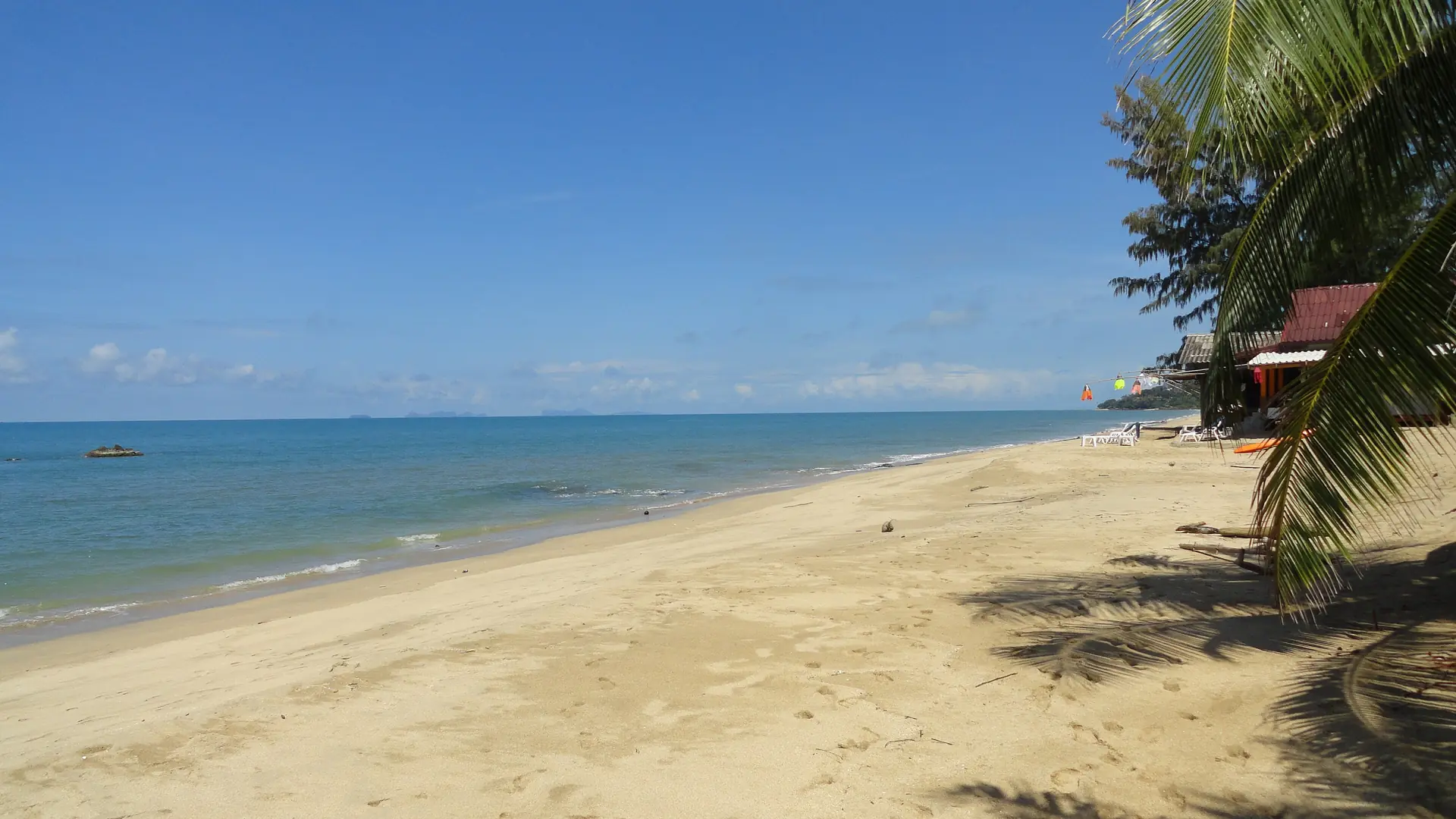 Palm shade and open blue water along Klong Nin Beach on Koh Lanta