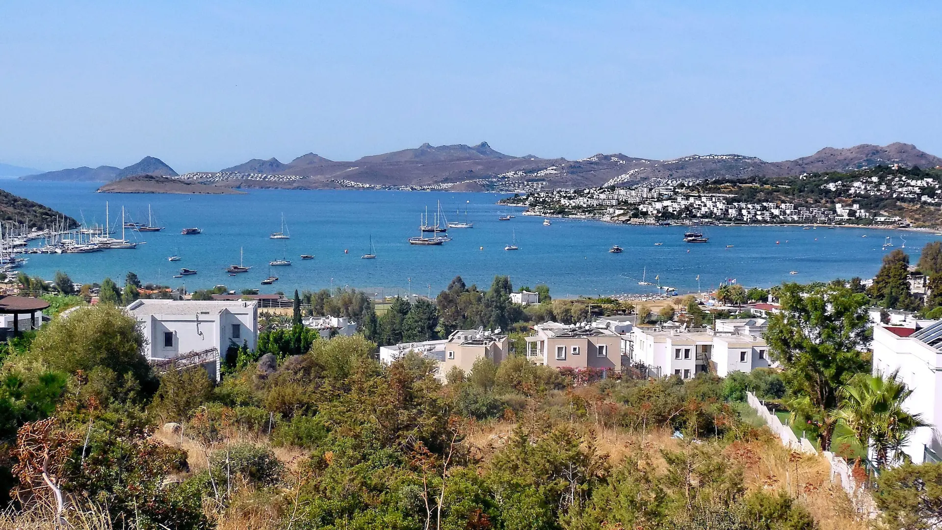 Sunny Bitez Bay with calm Aegean water, sailing boats and low white buildings