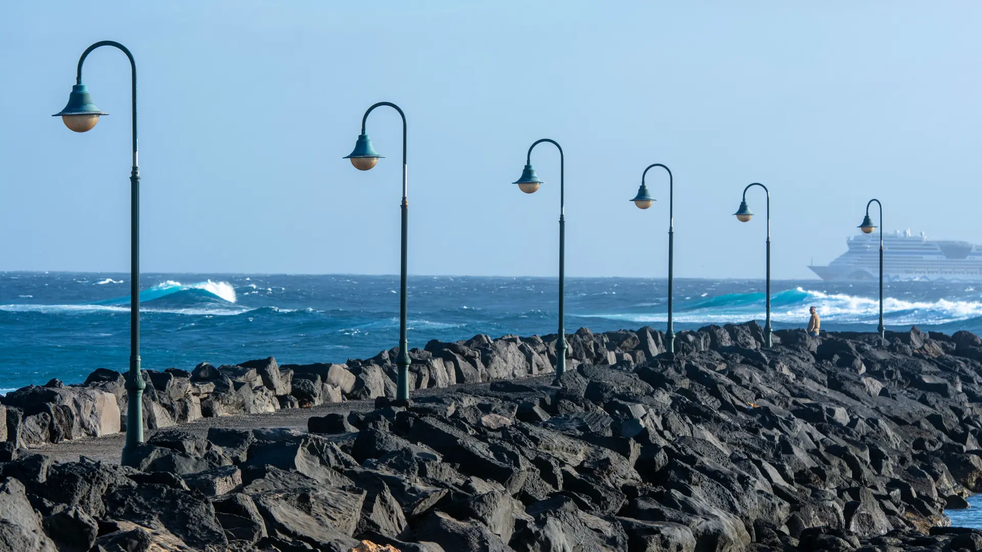 the black volcanic-stone breakwater in Ponta Delgada's harbour under bright Atlantic light