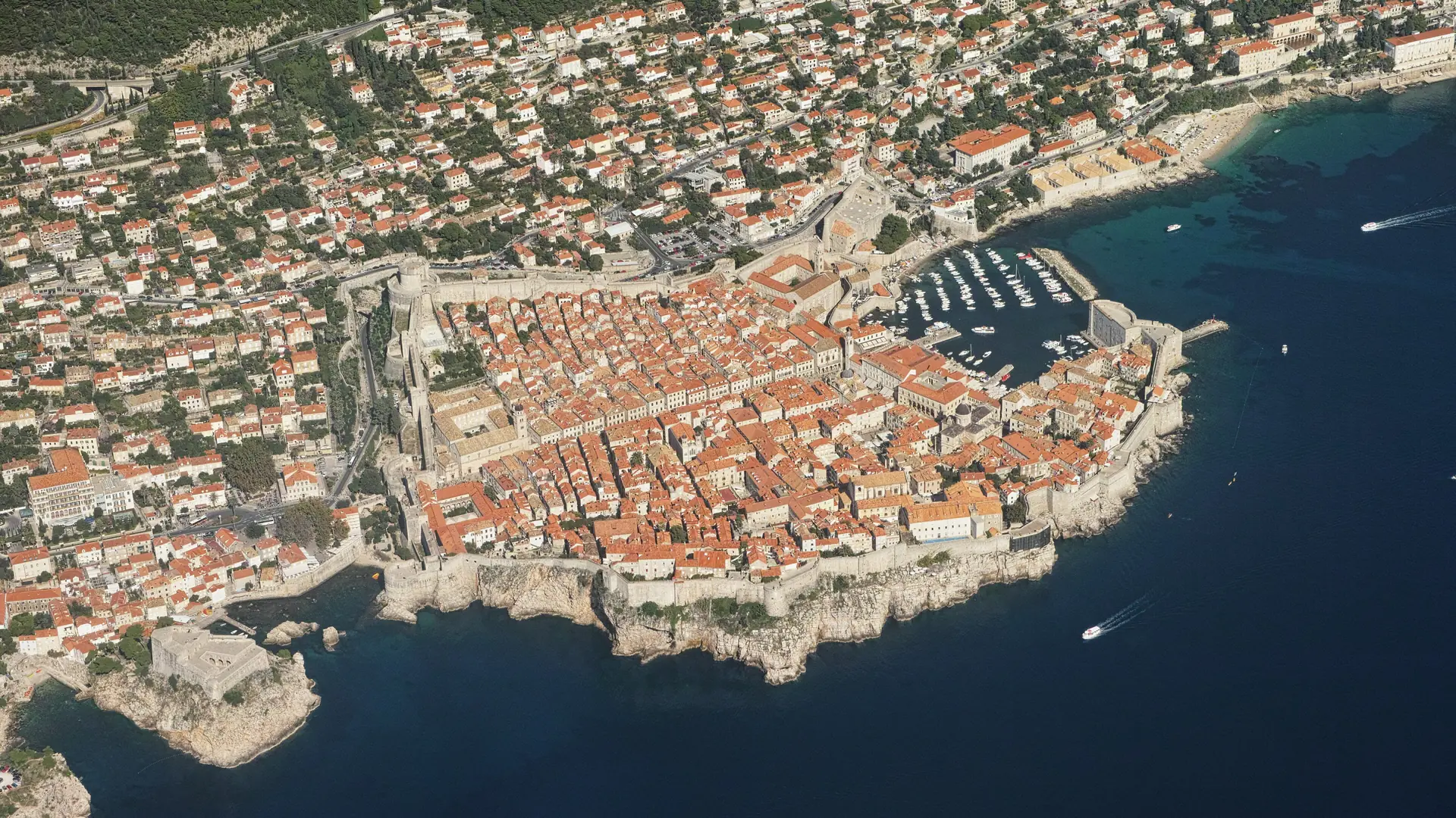 Sunlit aerial view over Dubrovnik's stone Old Town, orange roofs and the Adriatic