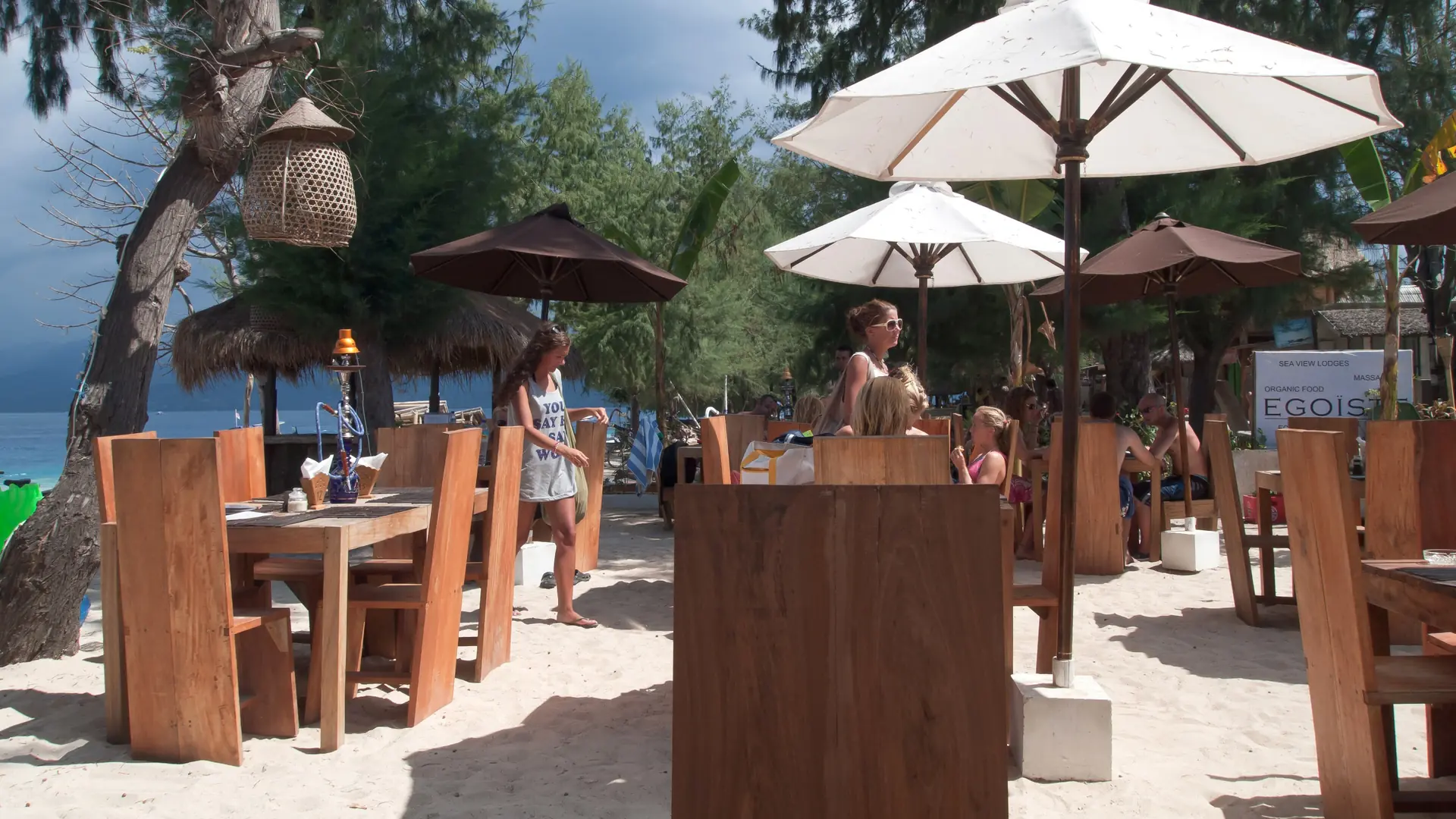 Outdoor café tables and white umbrellas beside Gili Trawangan’s blue sea