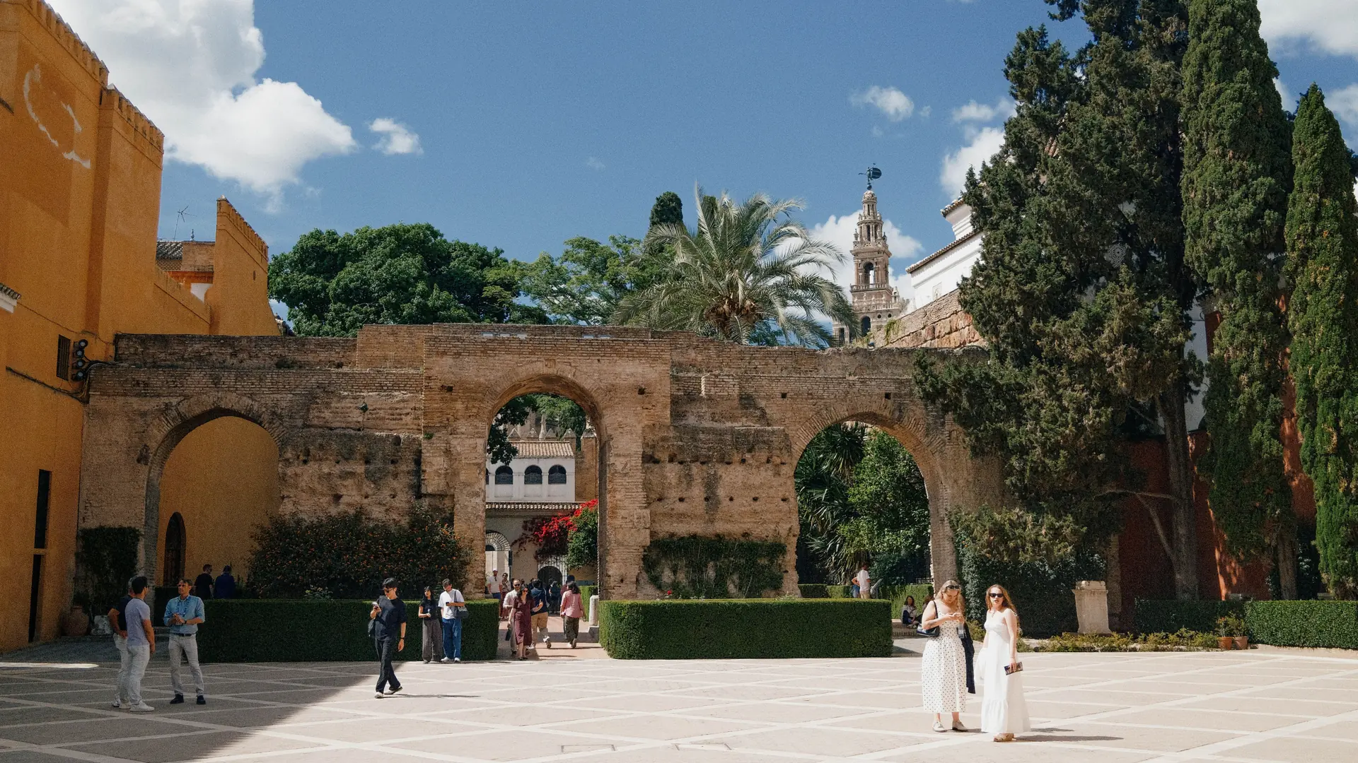 Three brick arches between the Real Alcázar courtyards, with the Giralda beyond