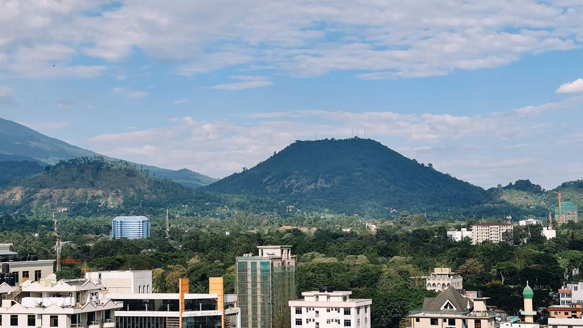 Sunlit Arusha cityscape with low hills beyond the buildings