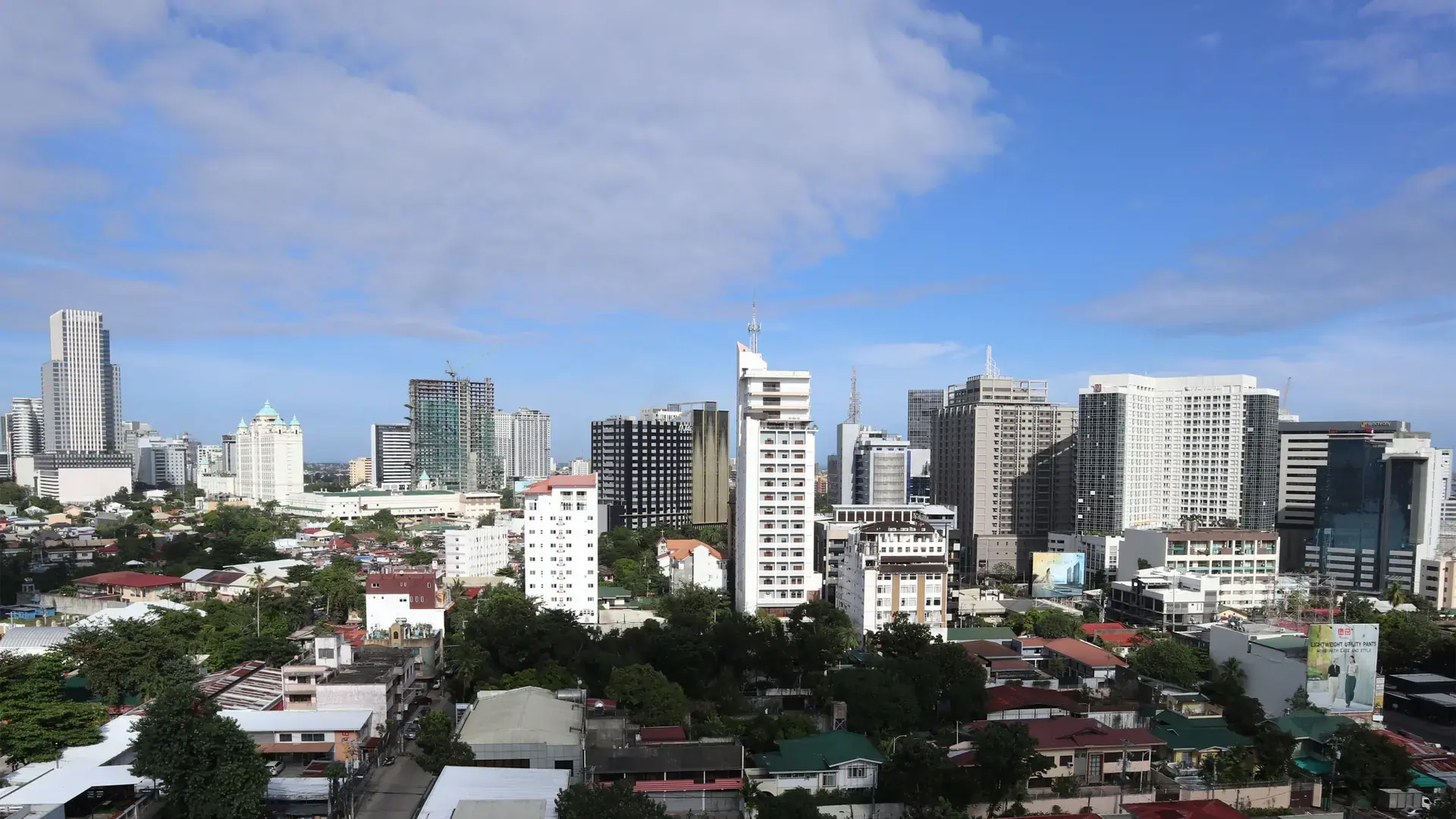 The Cebu Business Park skyline rising above low-rise rooftops under a blue sky
