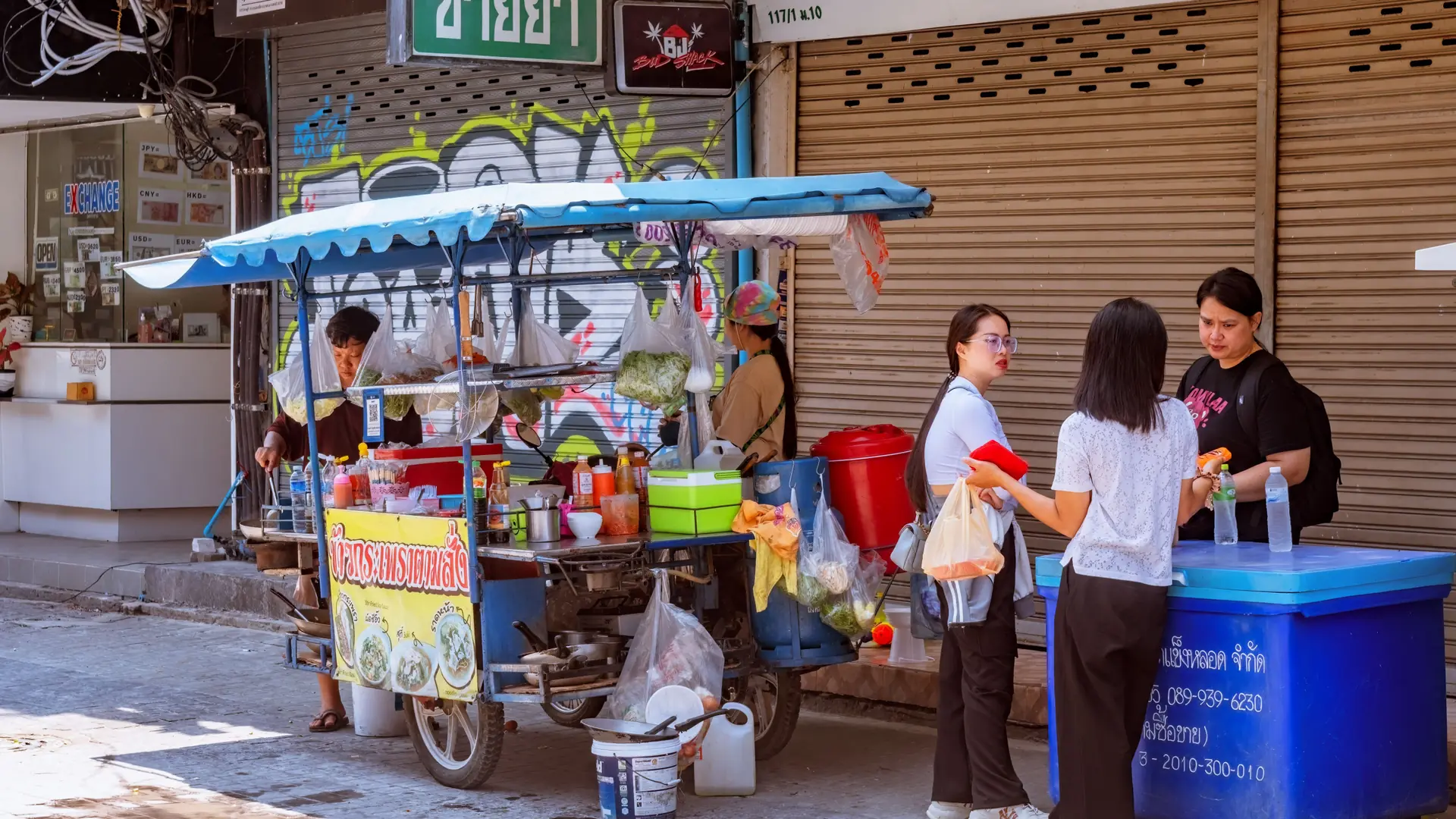 A Pattaya street-food vendor serving customers at an evening stall