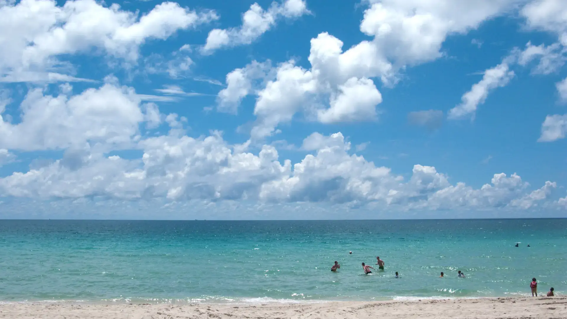 Sunny Koh Samui sand and blue Gulf water beneath white clouds
