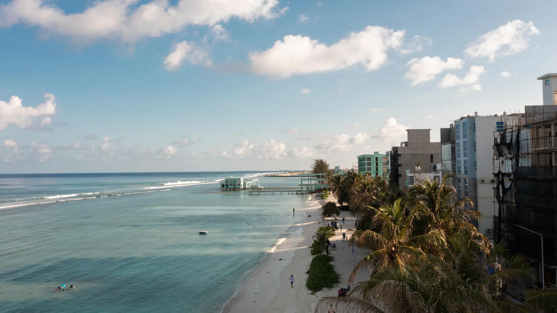 Elevated view along sunny Hulhumalé Beach with palms and guesthouses