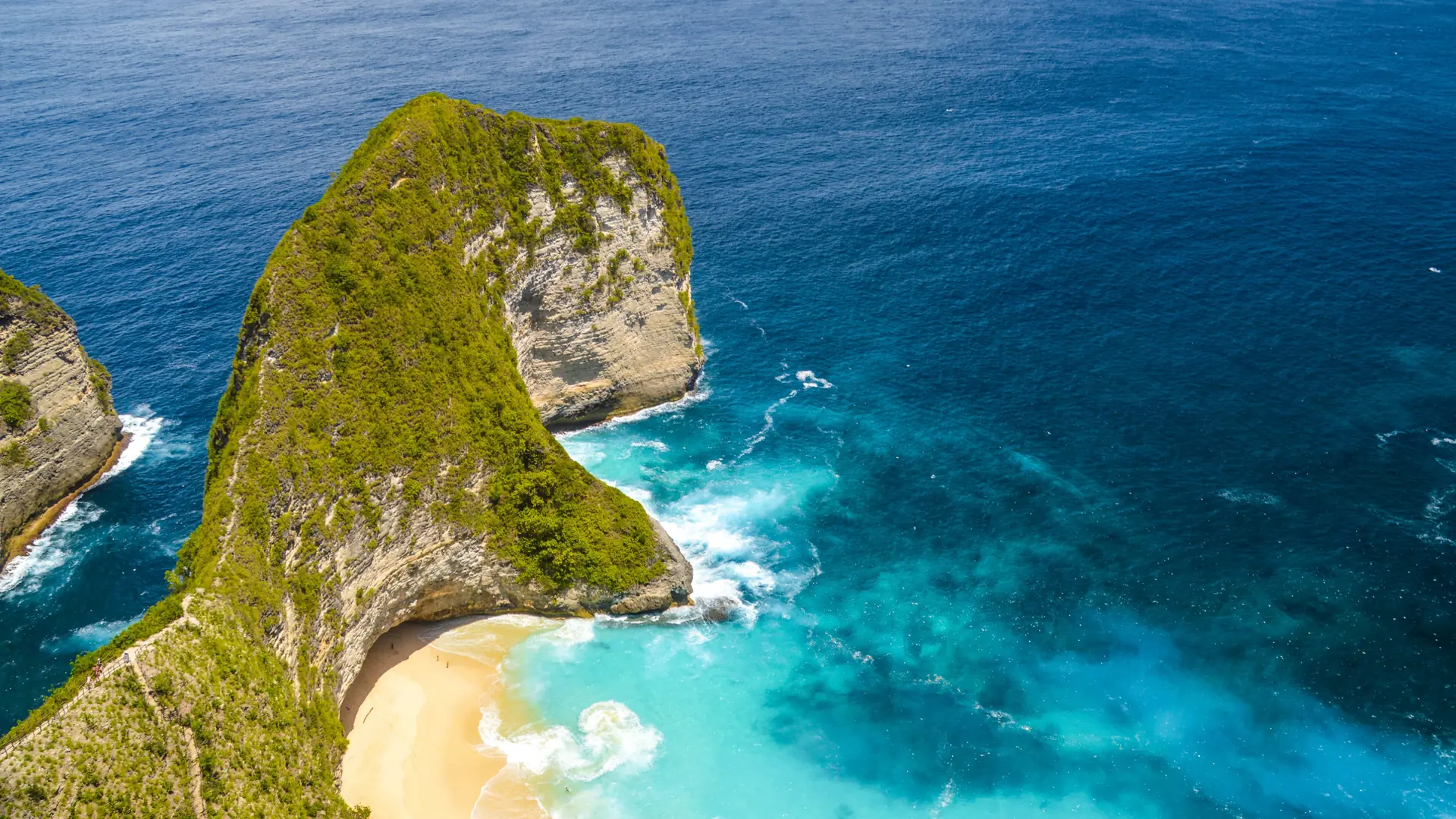 Kelingking’s green limestone headland above turquoise surf on Nusa Penida