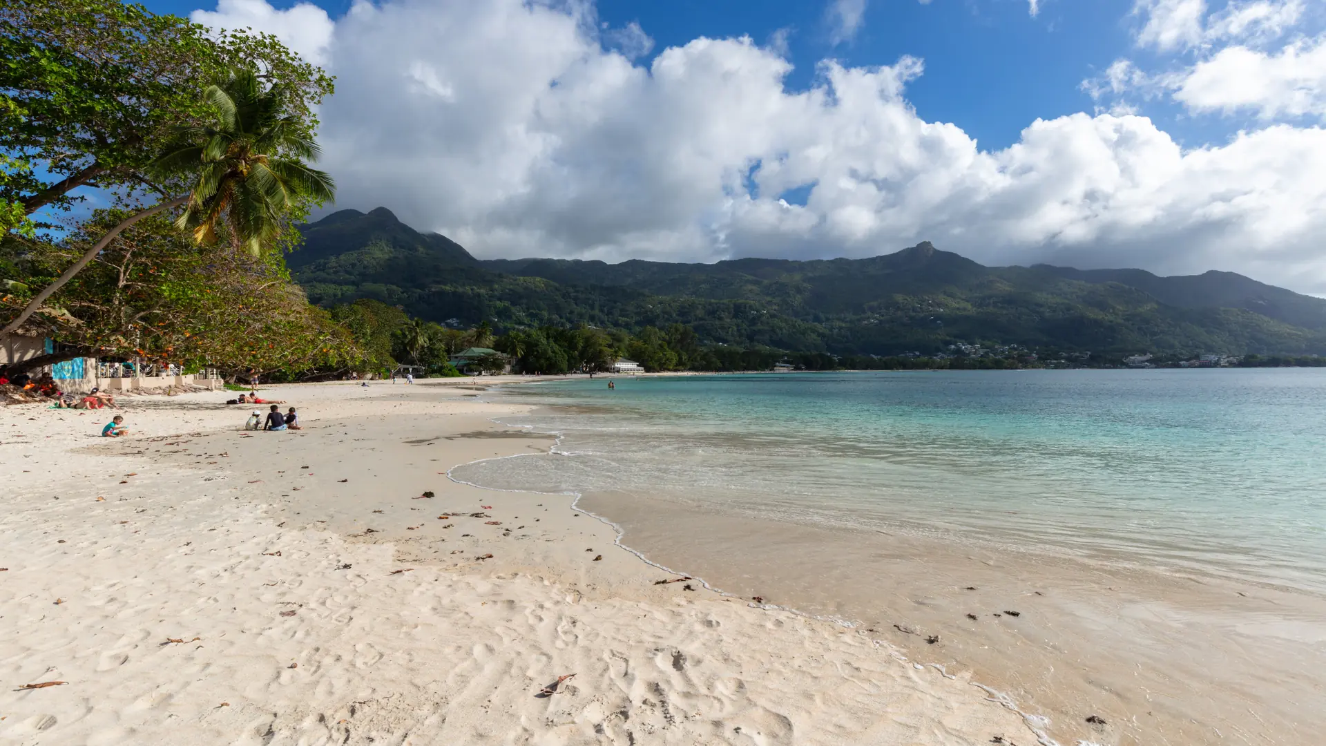 Sunlit Beau Vallon beach beneath Mahé’s wooded ridge