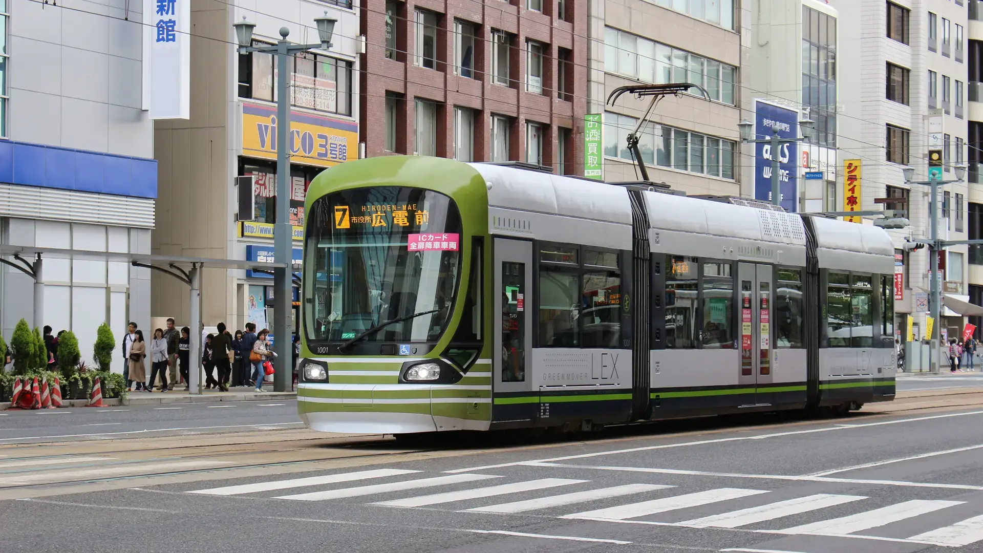 modern green tram crossing Hatchobori's busy central Hiroshima streets in daylight