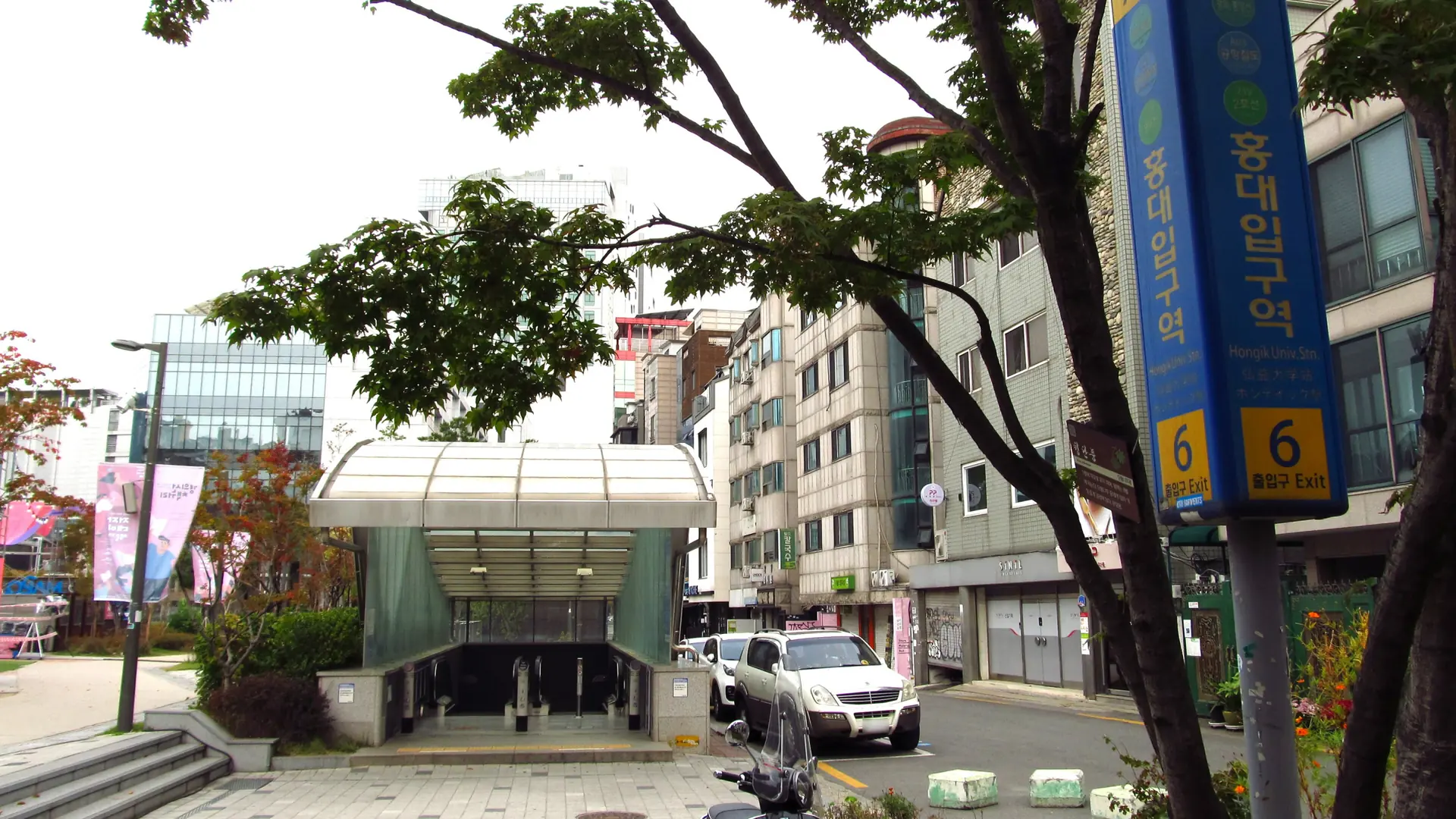 Exit 6 of Hongik University (Hongdae) Station, its blue Korean/English signage clearly visible, in daylight