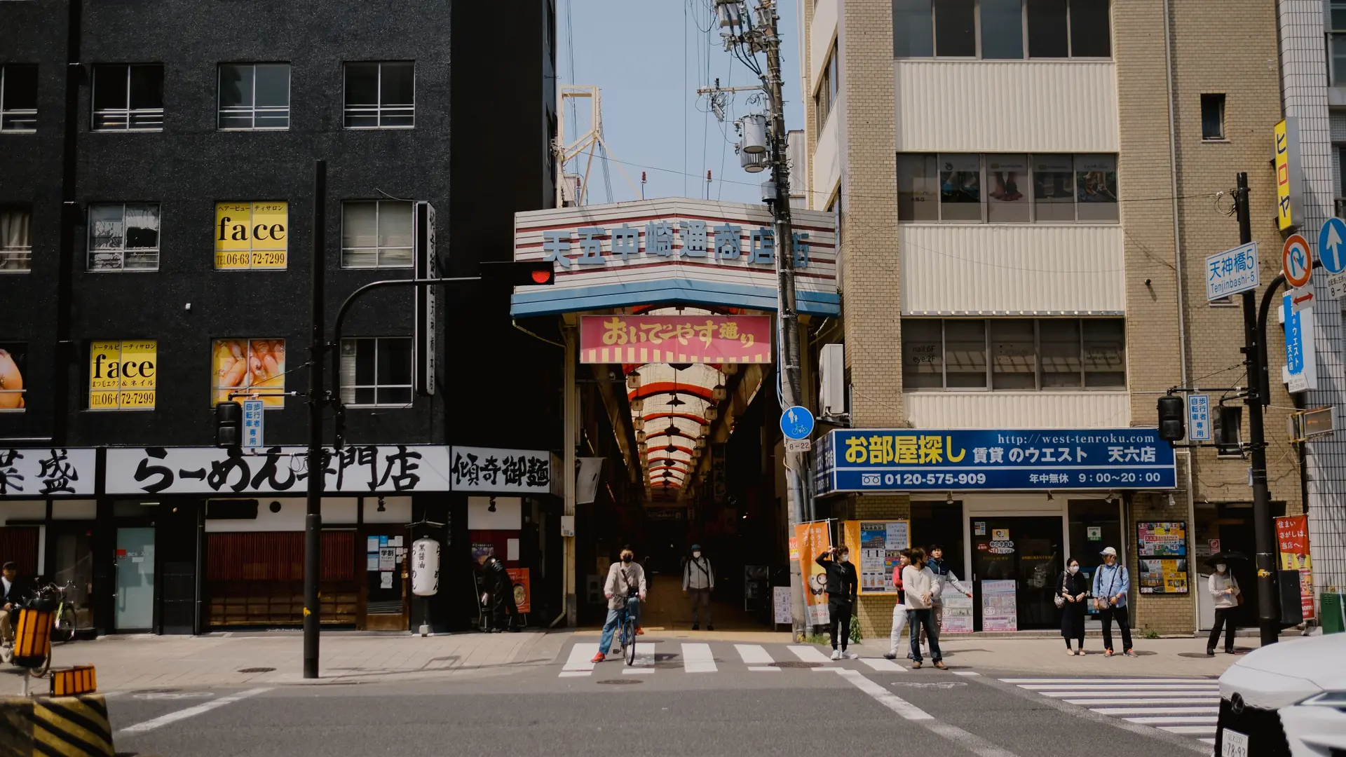 A sunlit Osaka shopping-arcade entrance beside the Tenjinbashi-5 street sign