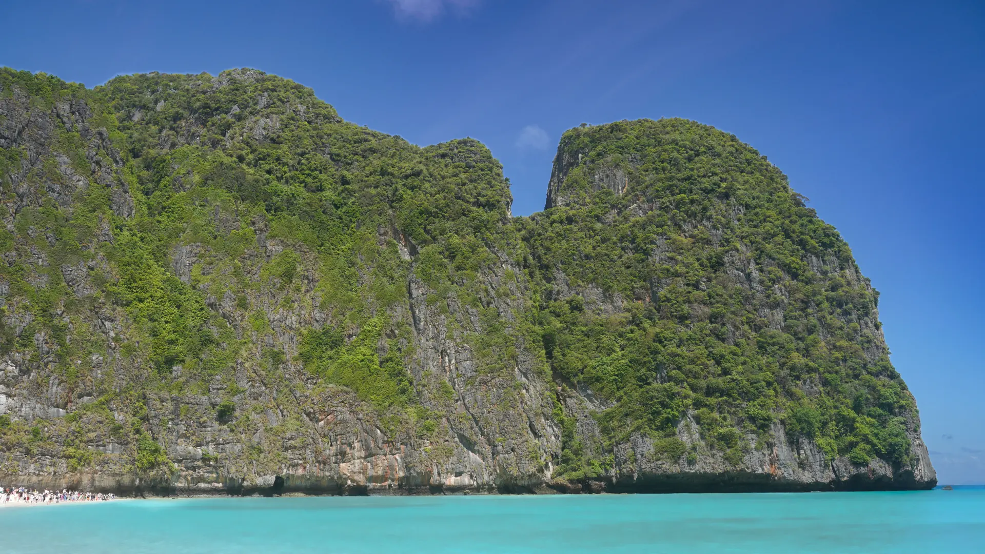 Sunlit limestone cliffs and turquoise water at Maya Bay, a wider Phi Phi scene