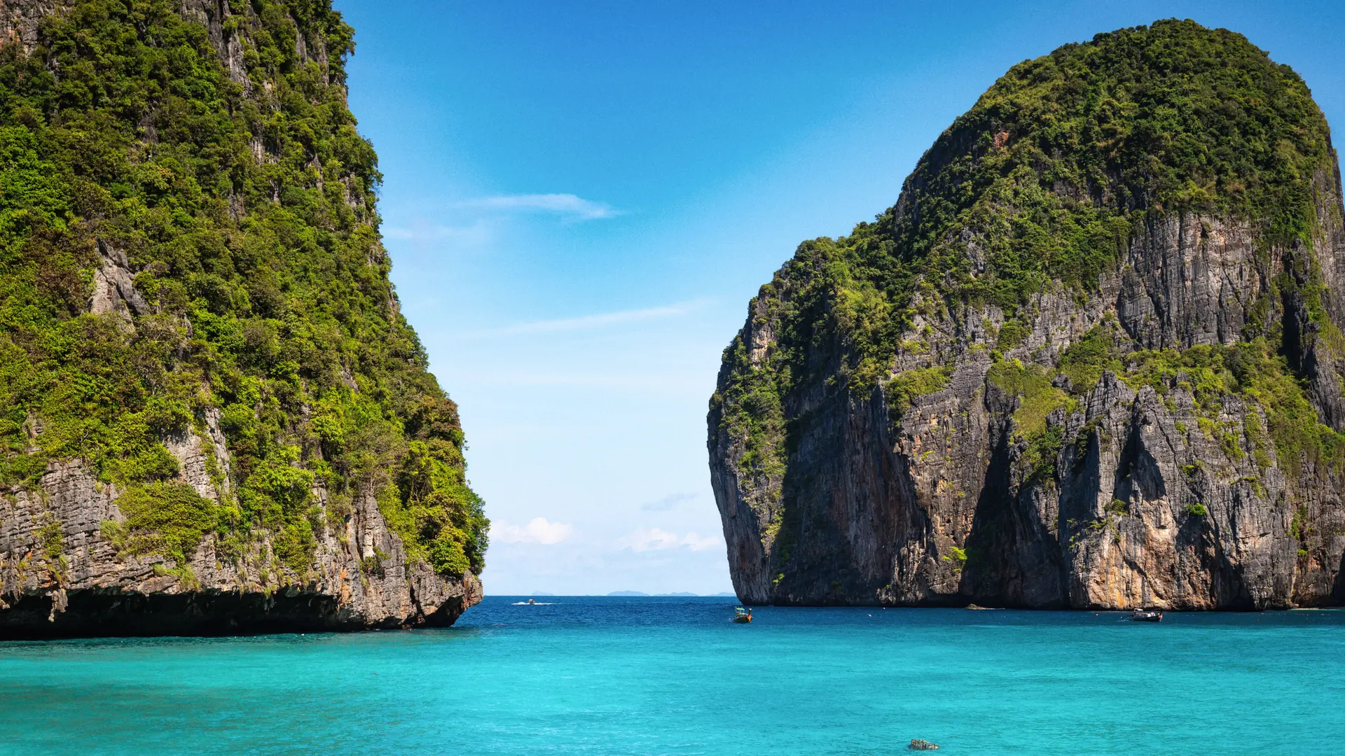 Sunlit limestone cliffs reflected in emerald Andaman water near Krabi