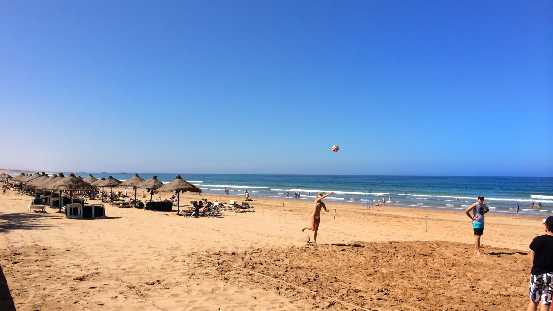 Sunlit Agadir beach with parasols, open sand and blue Atlantic water
