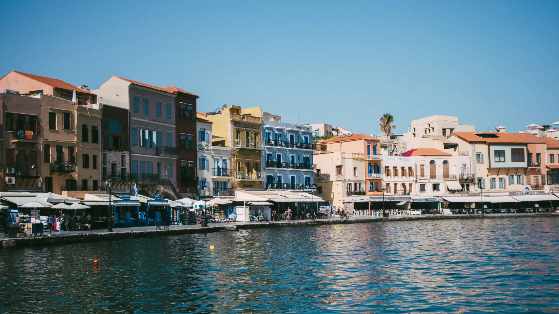 Colourful Venetian harbour houses reflected in the blue water at Chania, Crete