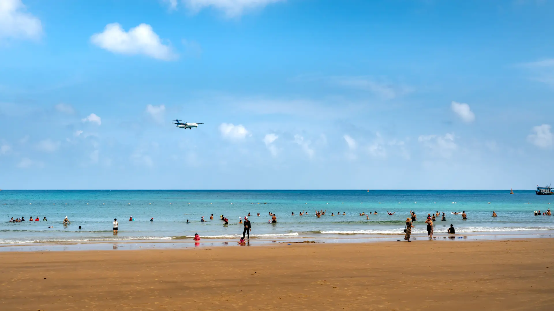 Visitors enjoying a sunny Phuket beach between palms and blue Andaman water