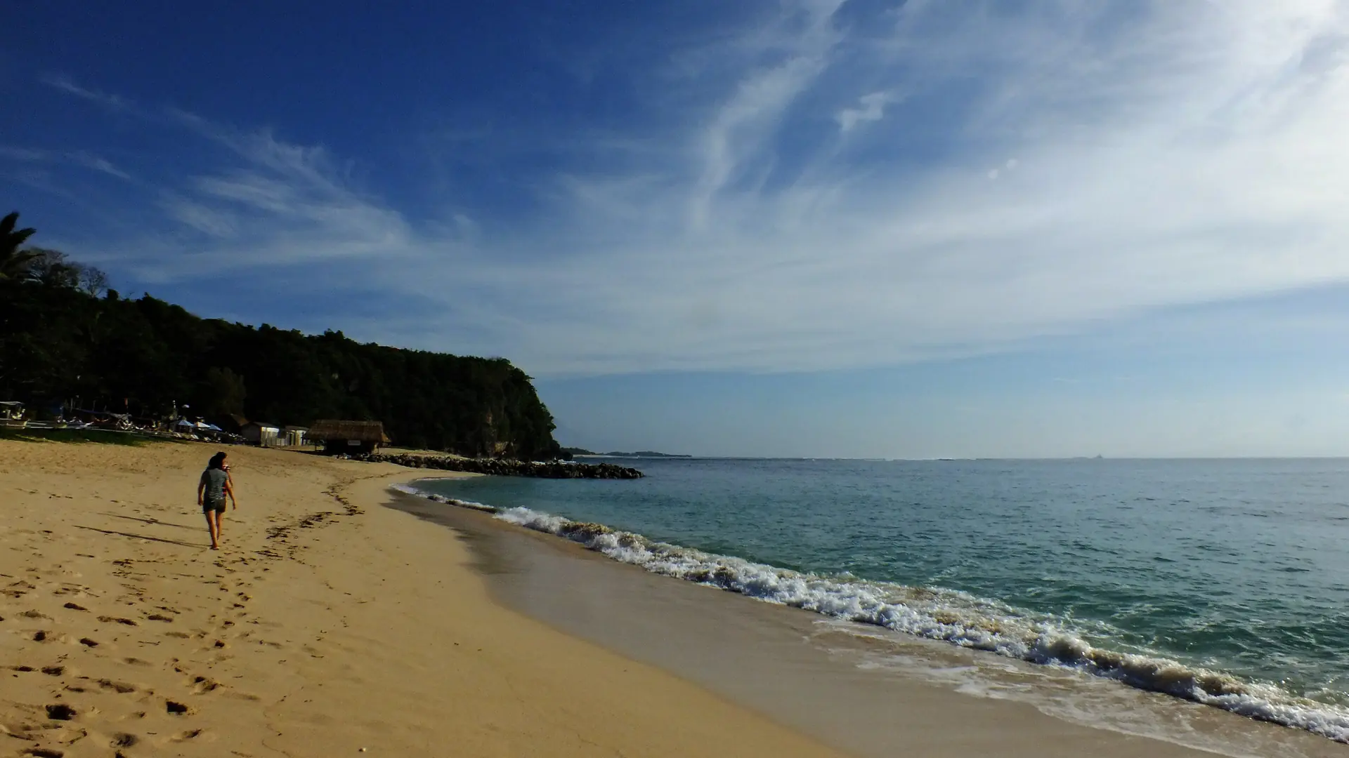 Morning light on a sandy beach and gentle breaking waves along the Sawangan coast in Nusa Dua, Bali