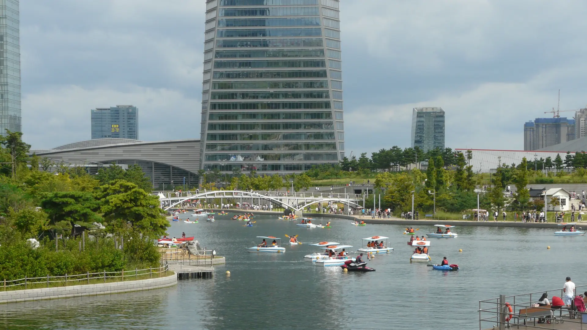 Pedal boats on Songdo Central Park's seawater canal beside modern buildings in Incheon