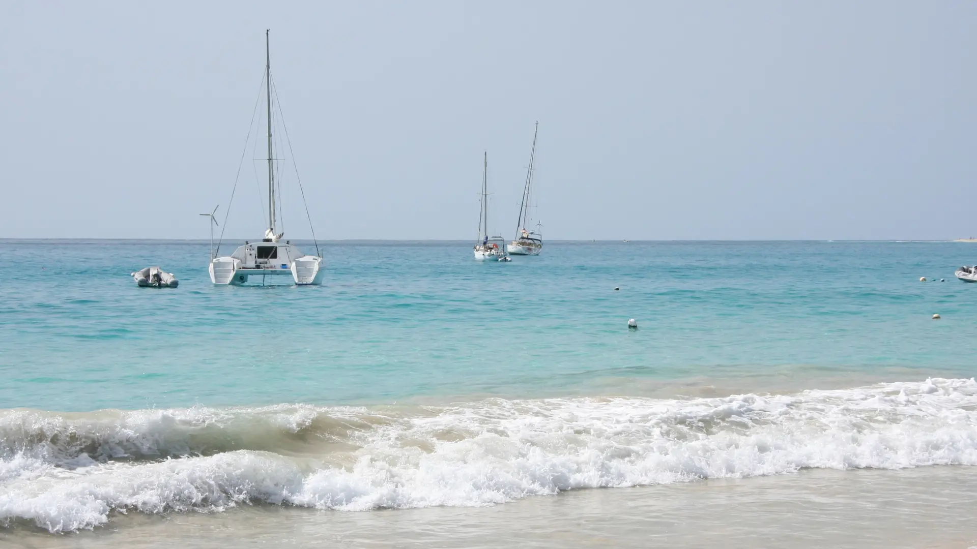 Daylit Santa Maria beach with Atlantic surf and sailboats on Sal