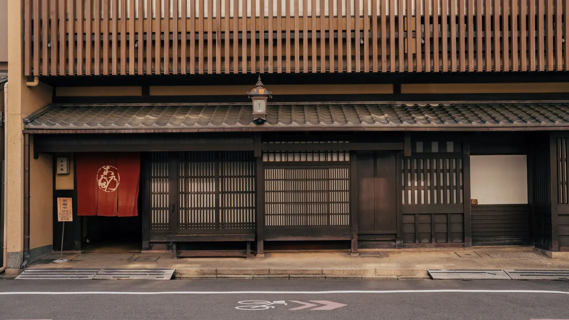 sunlit traditional wooden machiya facade on a quiet Kyoto street