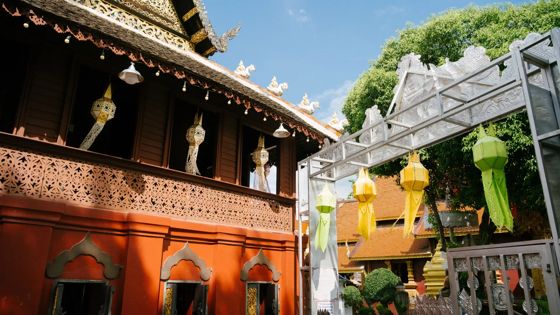 Colourful lanterns hanging beside carved temple architecture in Chiang Mai
