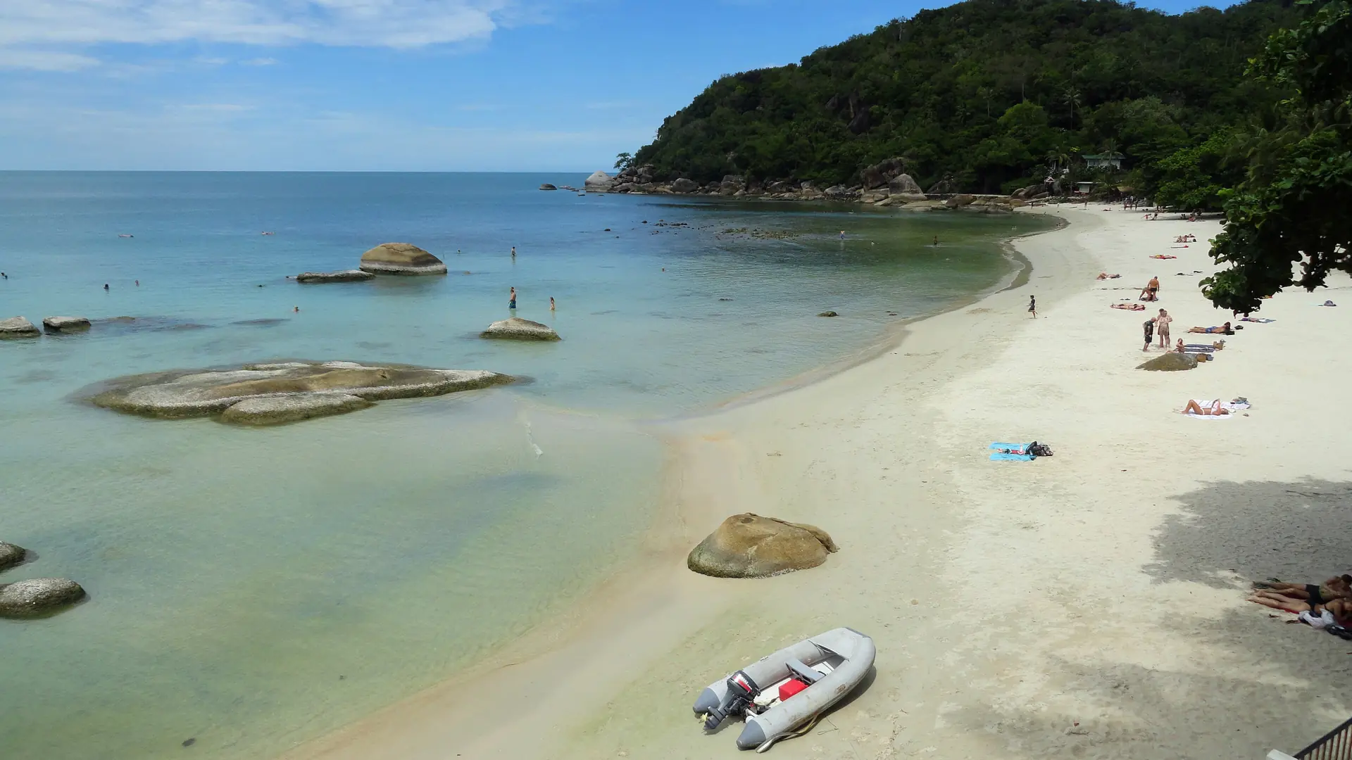 Clear shallow water and a green headland at Silver Beach on Koh Samui