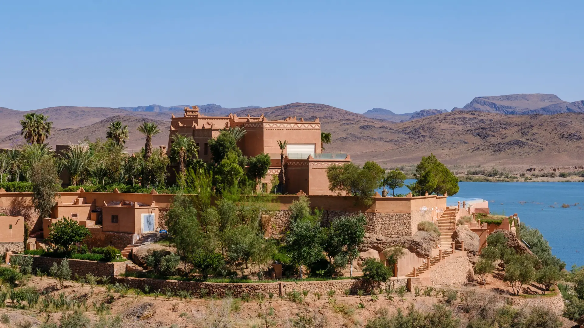 Ouarzazate buildings and palms beside the lake in daylight
