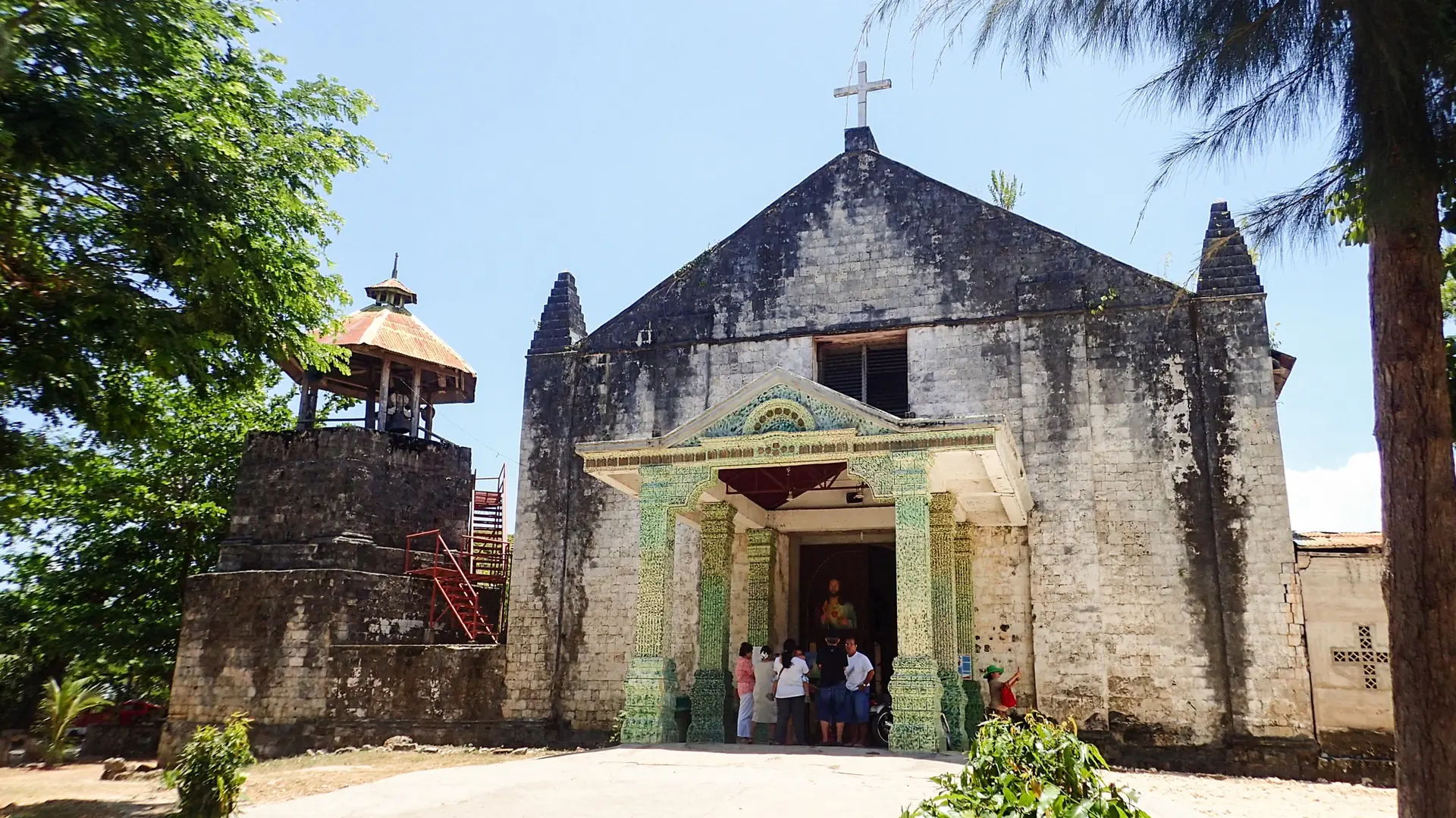 Stone facade, roof cross and attached bell tower of Divine Providence Church in Maria, Siquijor