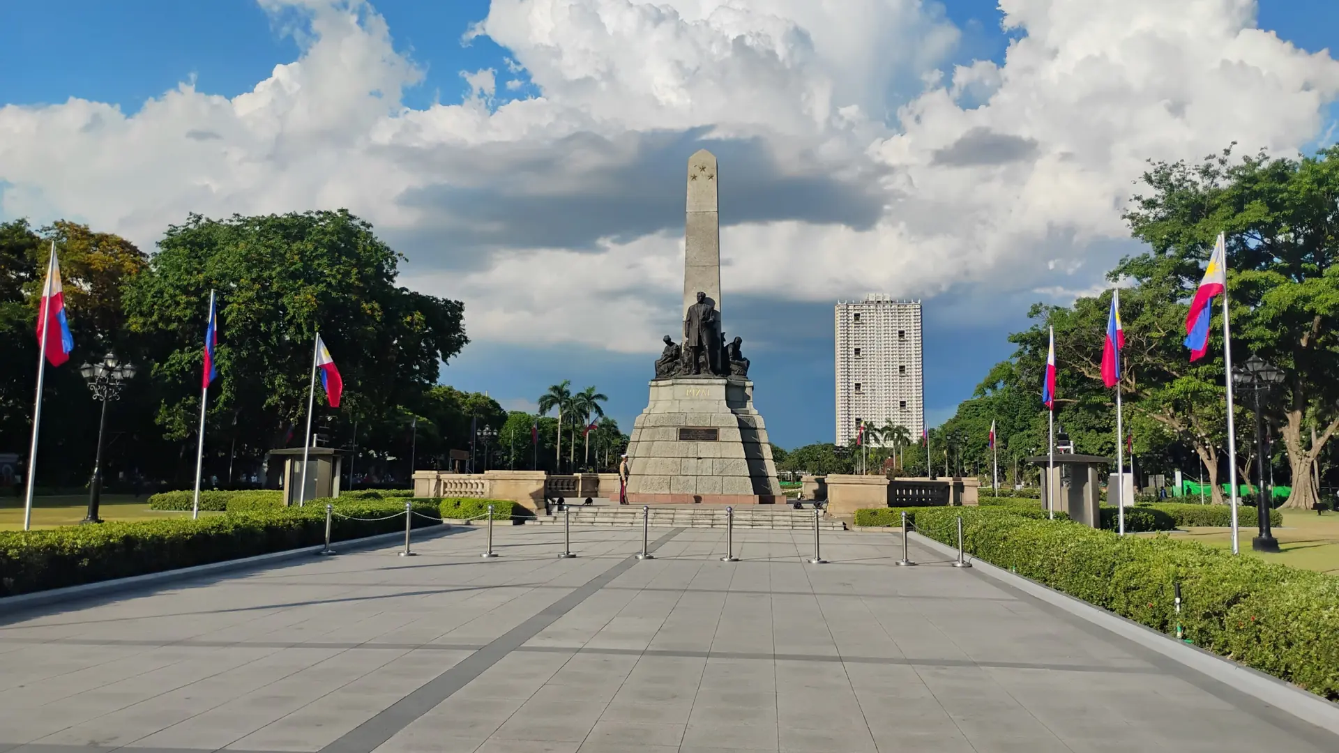 The Rizal Monument, flags and garden paths in Manila’s Rizal Park in daylight