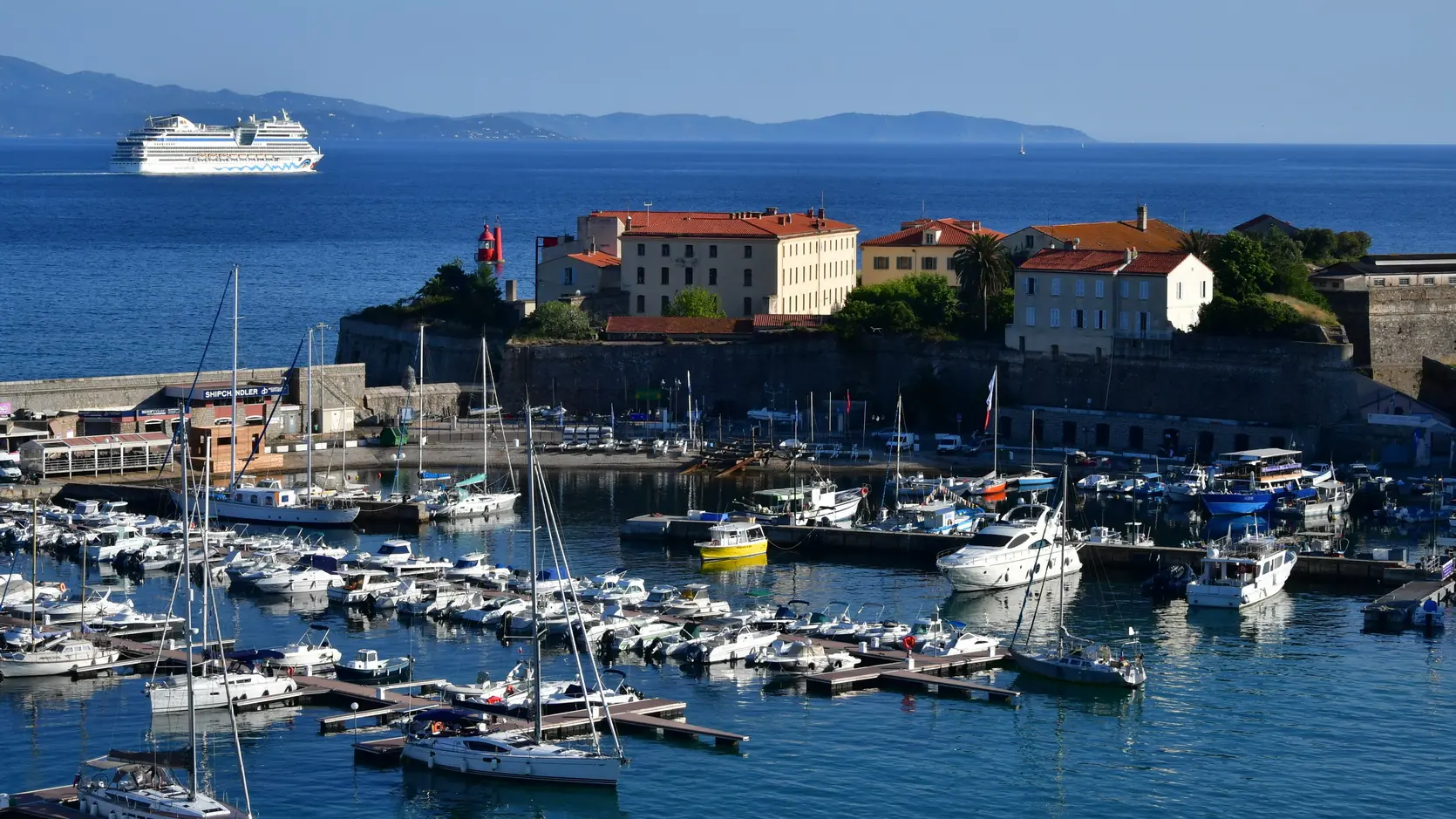 Boats in Ajaccio’s Port Tino Rossi below the stone citadel, with the blue gulf beyond