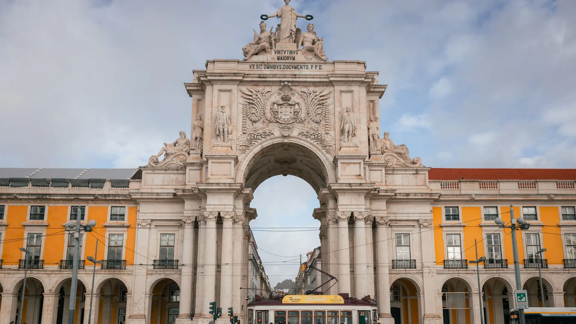 the Rua Augusta Arch in Baixa, Lisbon, with a red tram passing beneath it
