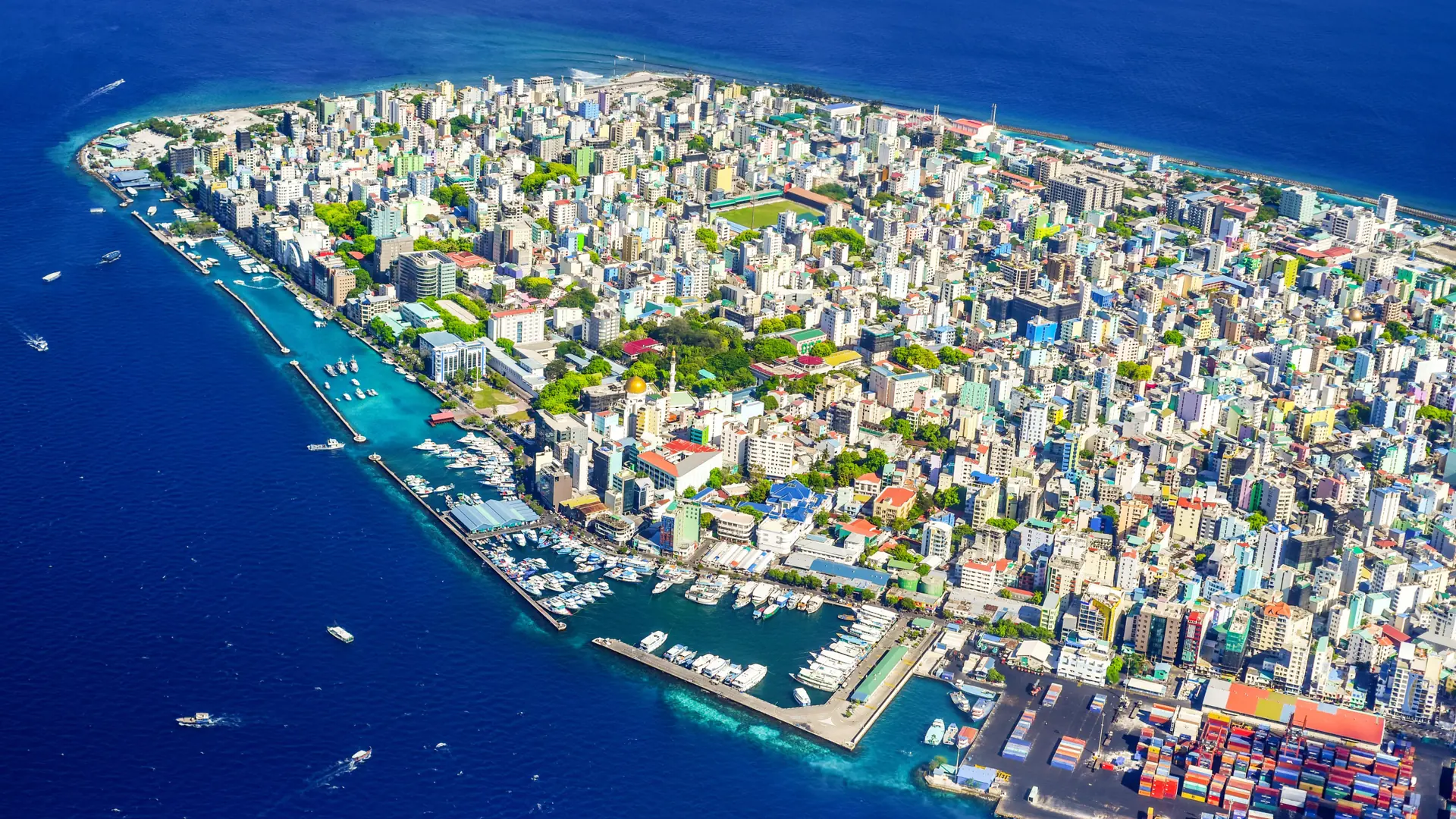 Sunlit Malé island waterfront and closely packed city buildings in clear daylight