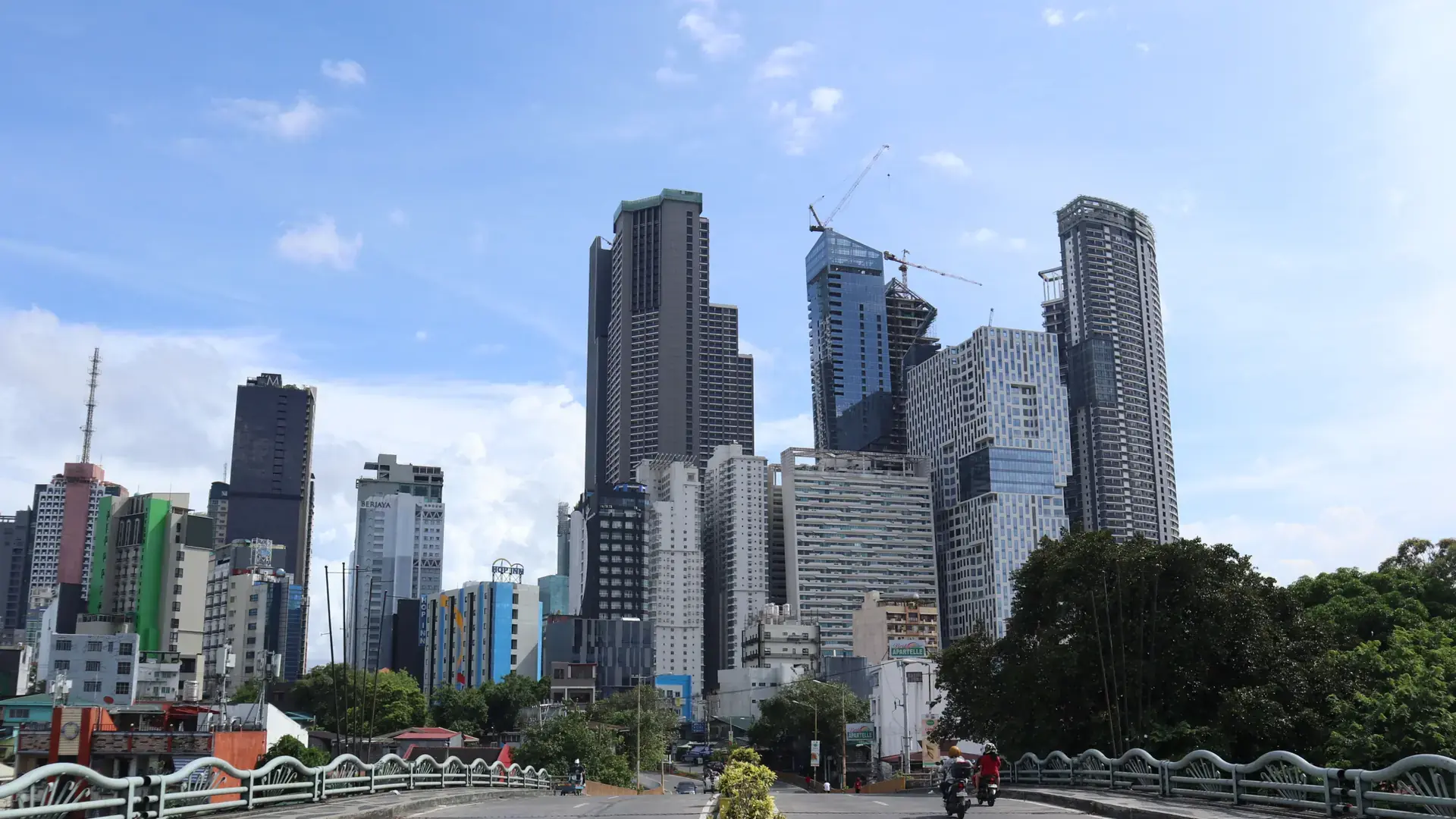 Poblacion’s towers and nearby Makati skyline beyond a bridge under a blue sky