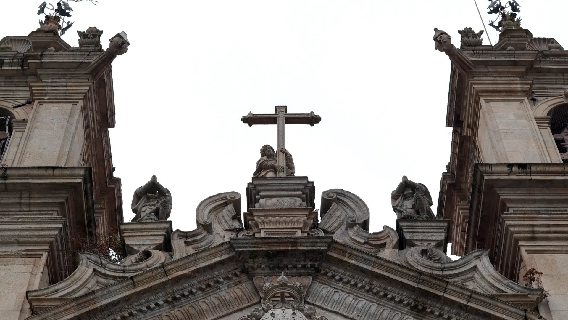 Baroque stonework, statues and cross on a historic Braga church façade