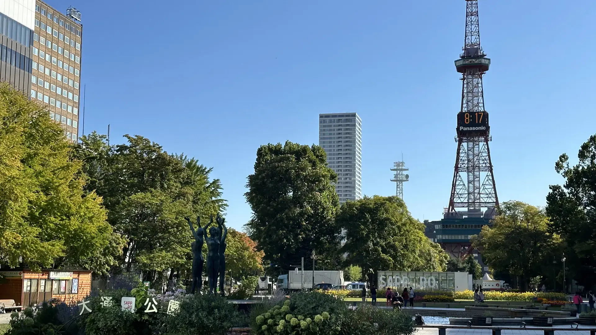sunlit flowerbeds and trees in Odori Park with Sapporo TV Tower beyond