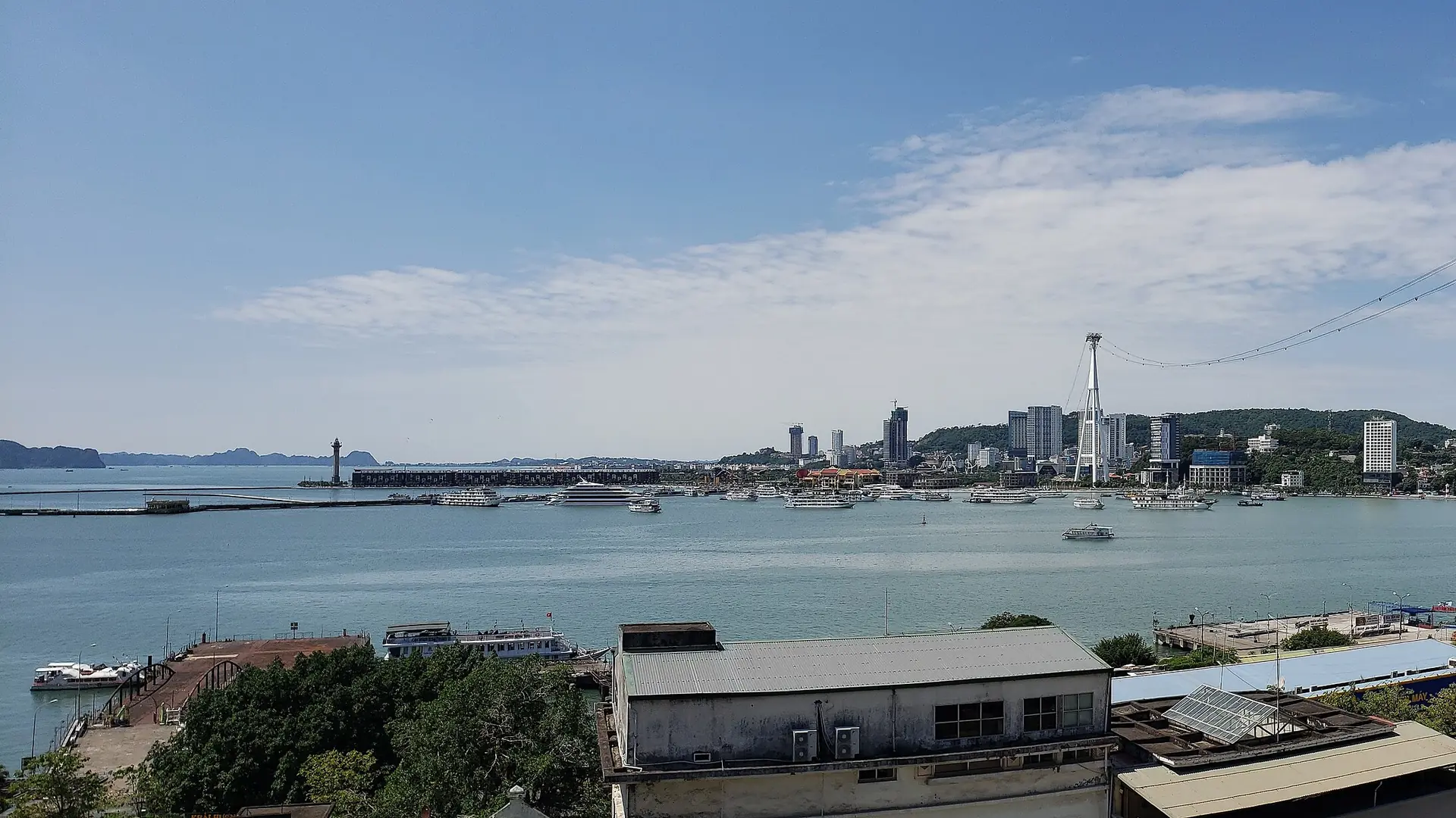 Bai Chay's waterfront and city skyline seen across the sunlit water from Hon Gai