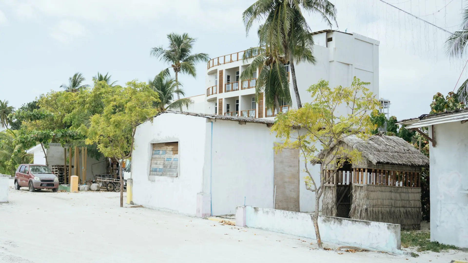 Sunlit sandy lane and guesthouse buildings on Maafushi