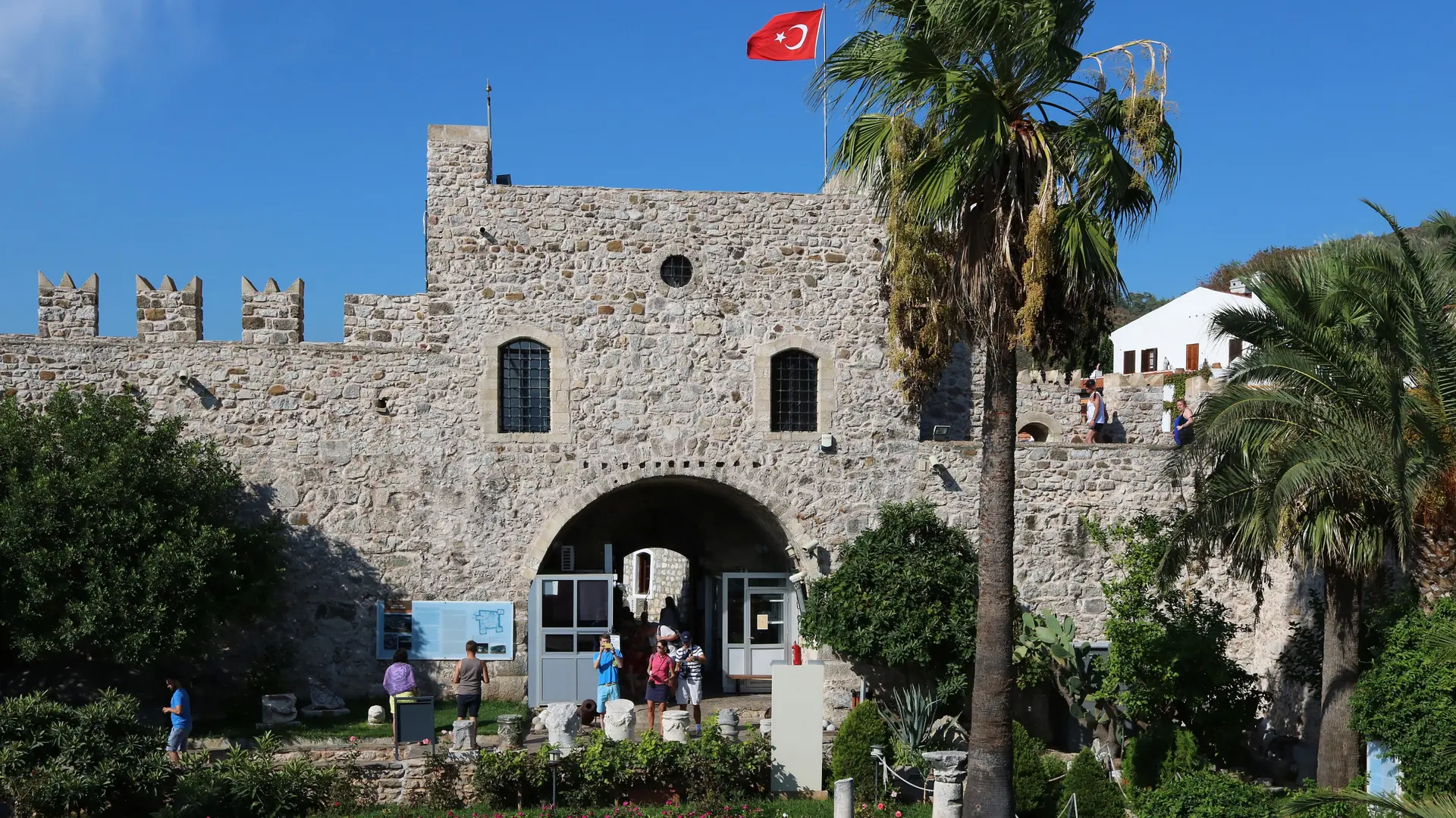 Sunlit stone entrance, crenellated walls and palms at Marmaris Castle Museum