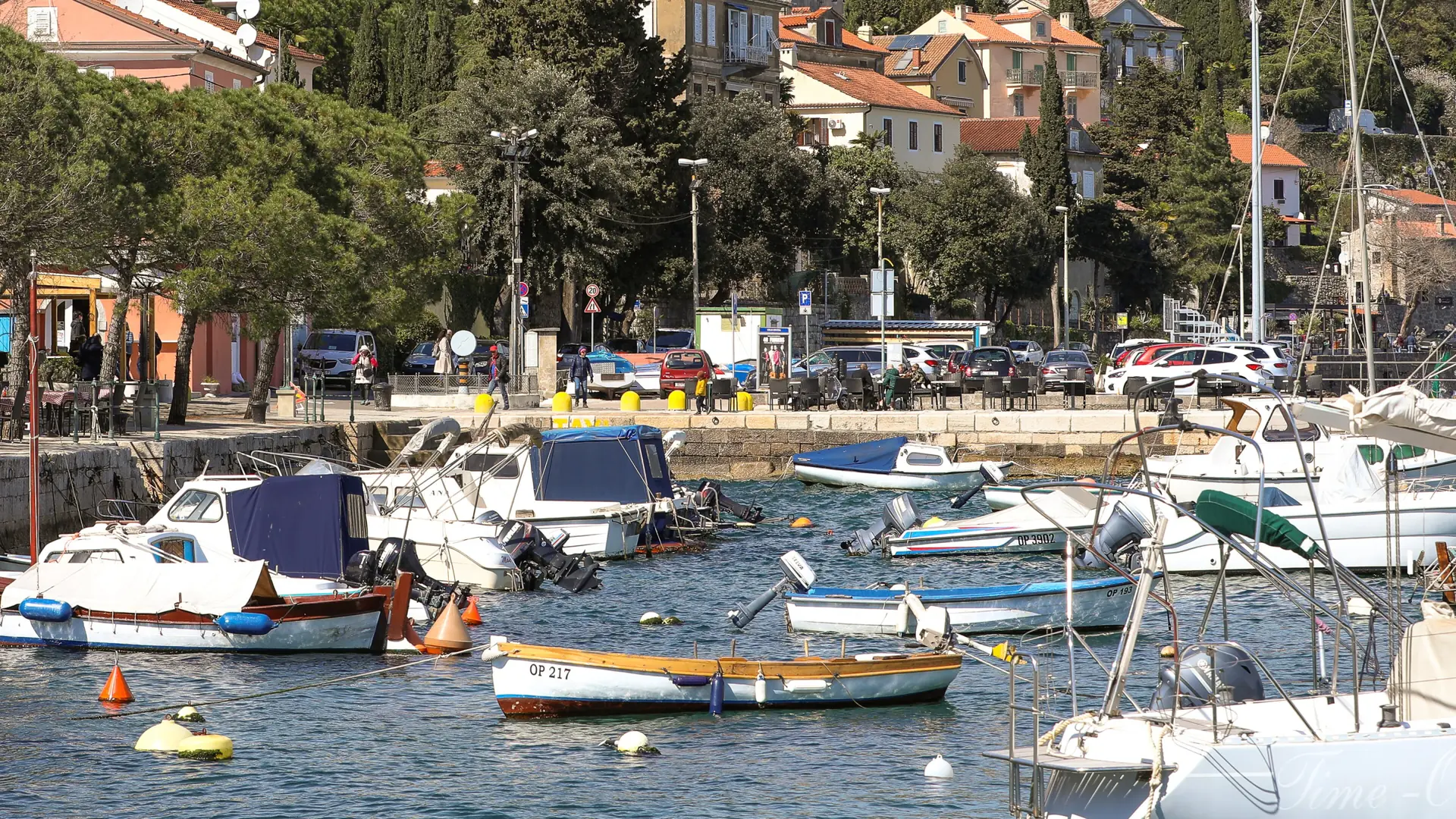 Small boats moored below the waterfront buildings and trees at Volosko harbour