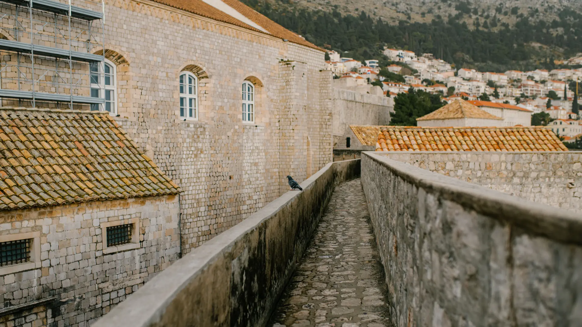 A stone walkway atop Dubrovnik's old city walls, overlooking terracotta rooftops